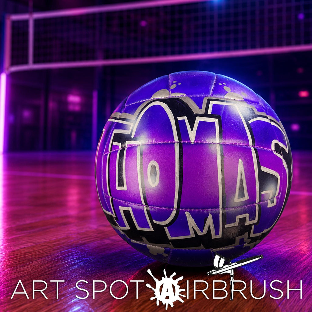 A purple volleyball with the word "TOMAS" written on it, placed on a wooden surface with a purple and black background.