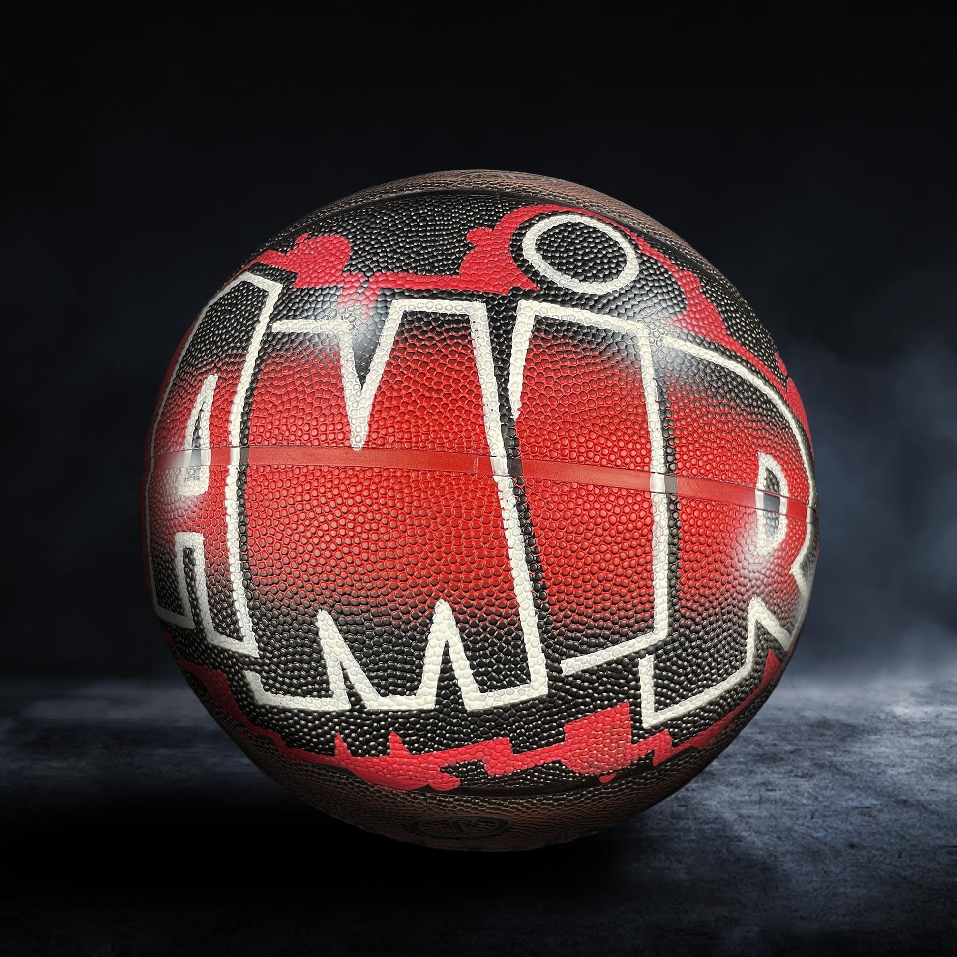 A basketball with the word "AMR" painted on it, featuring a red and black color scheme.