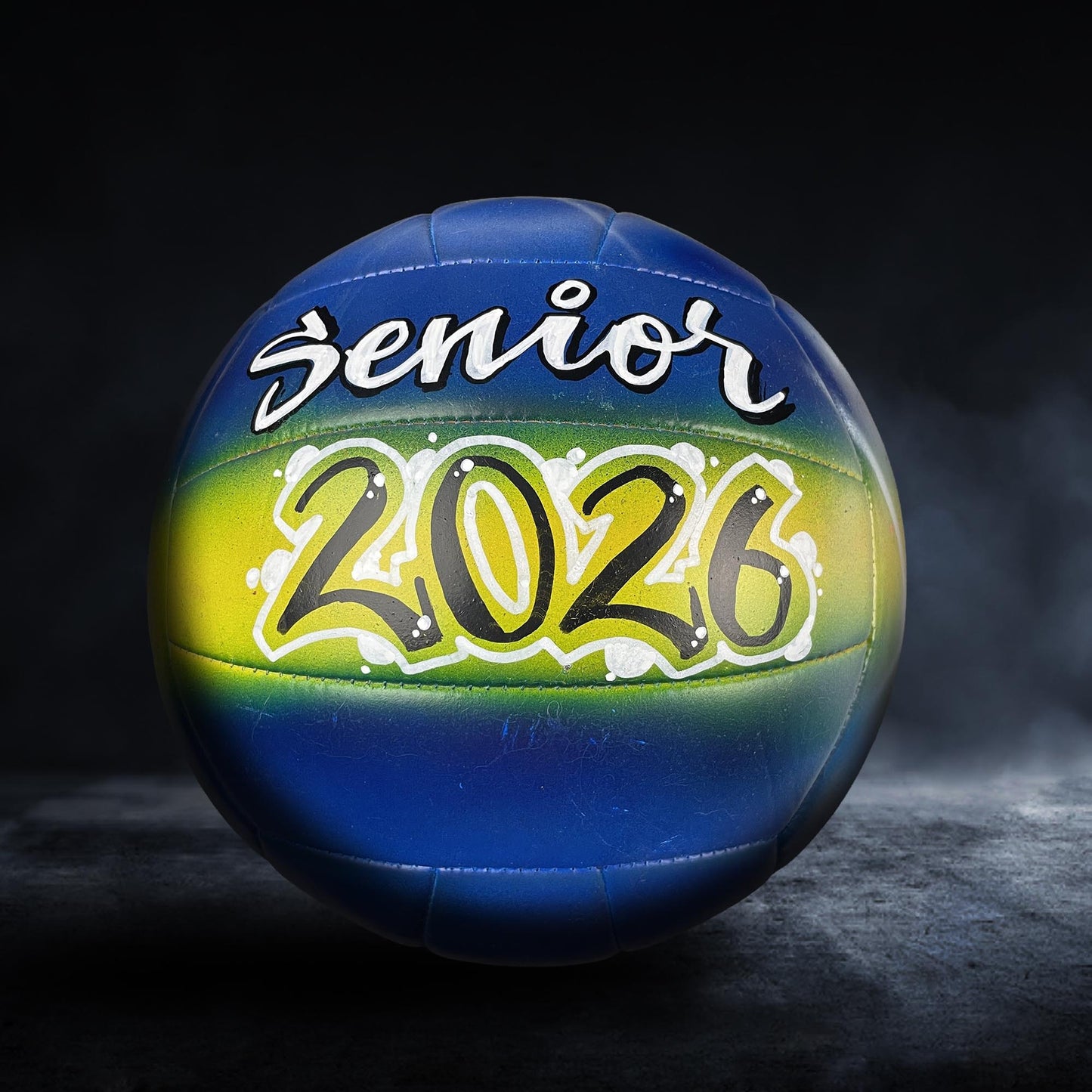 A blue and yellow volleyball with the text "senior 2026" written on it.
