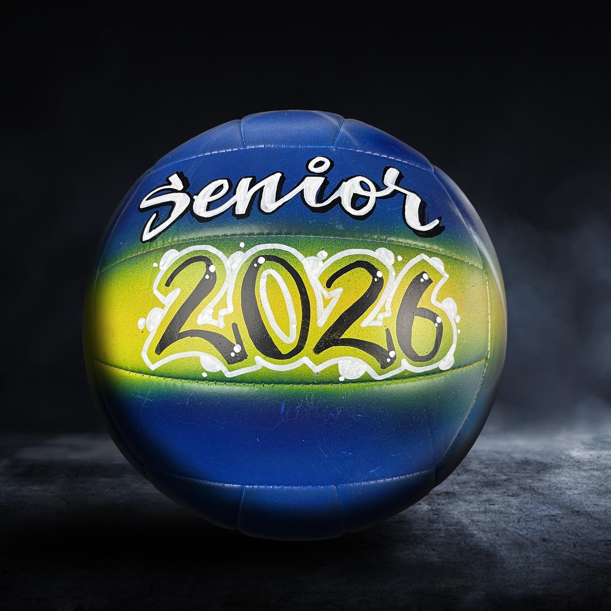 A blue and yellow volleyball with the text "senior 2026" written on it.