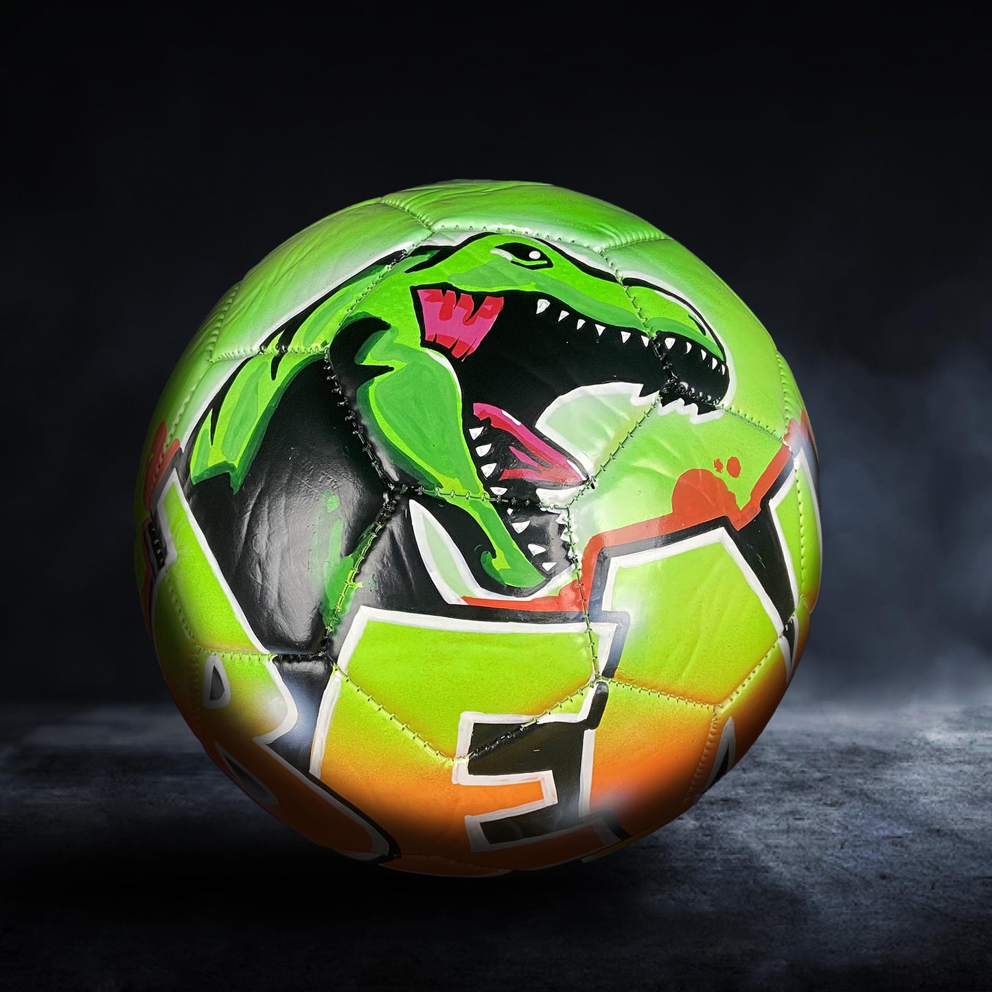 A soccer ball with a dinosaur design on it.