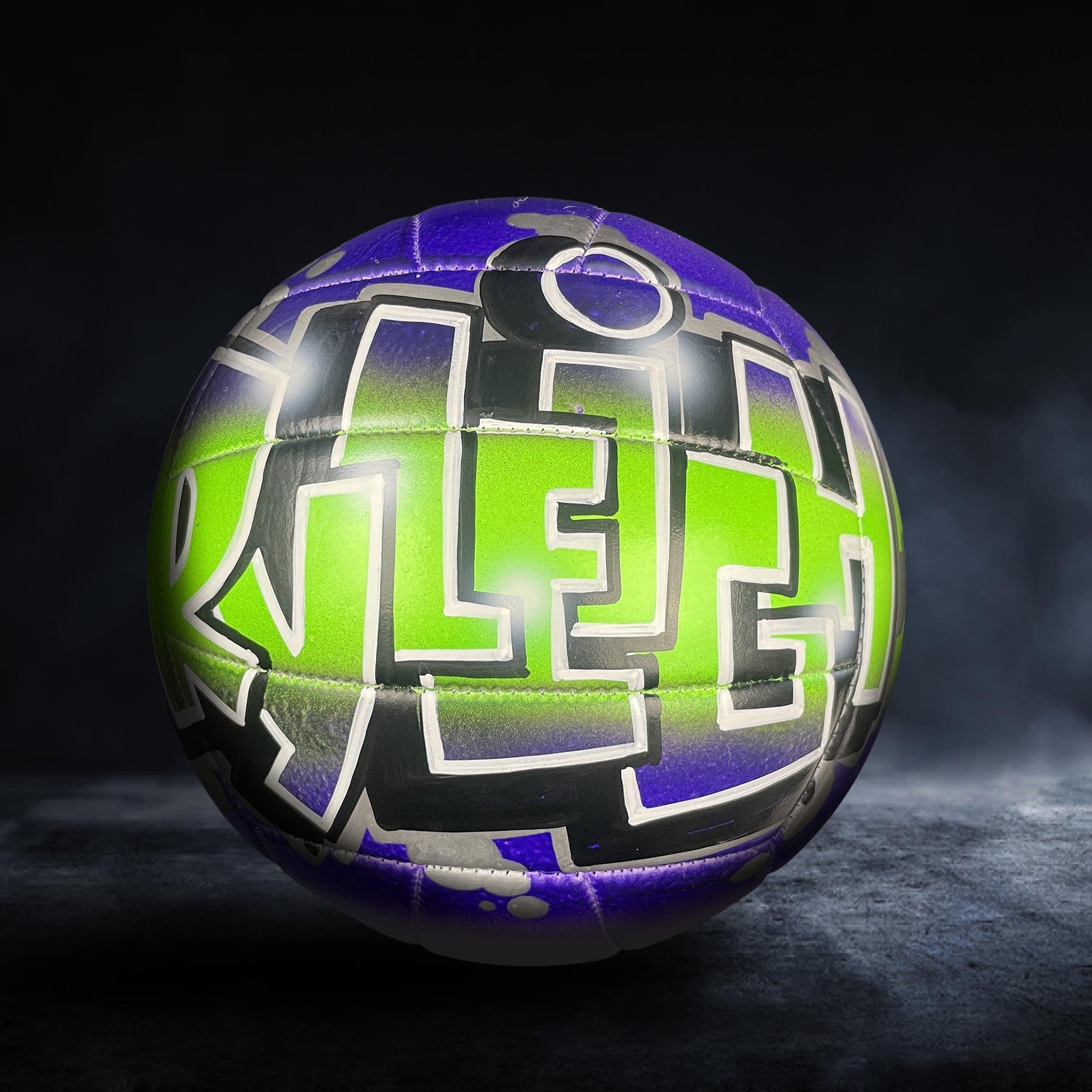 A colorful, graffiti-style soccer ball with the word "ALEX" painted on it, set against a dark background.