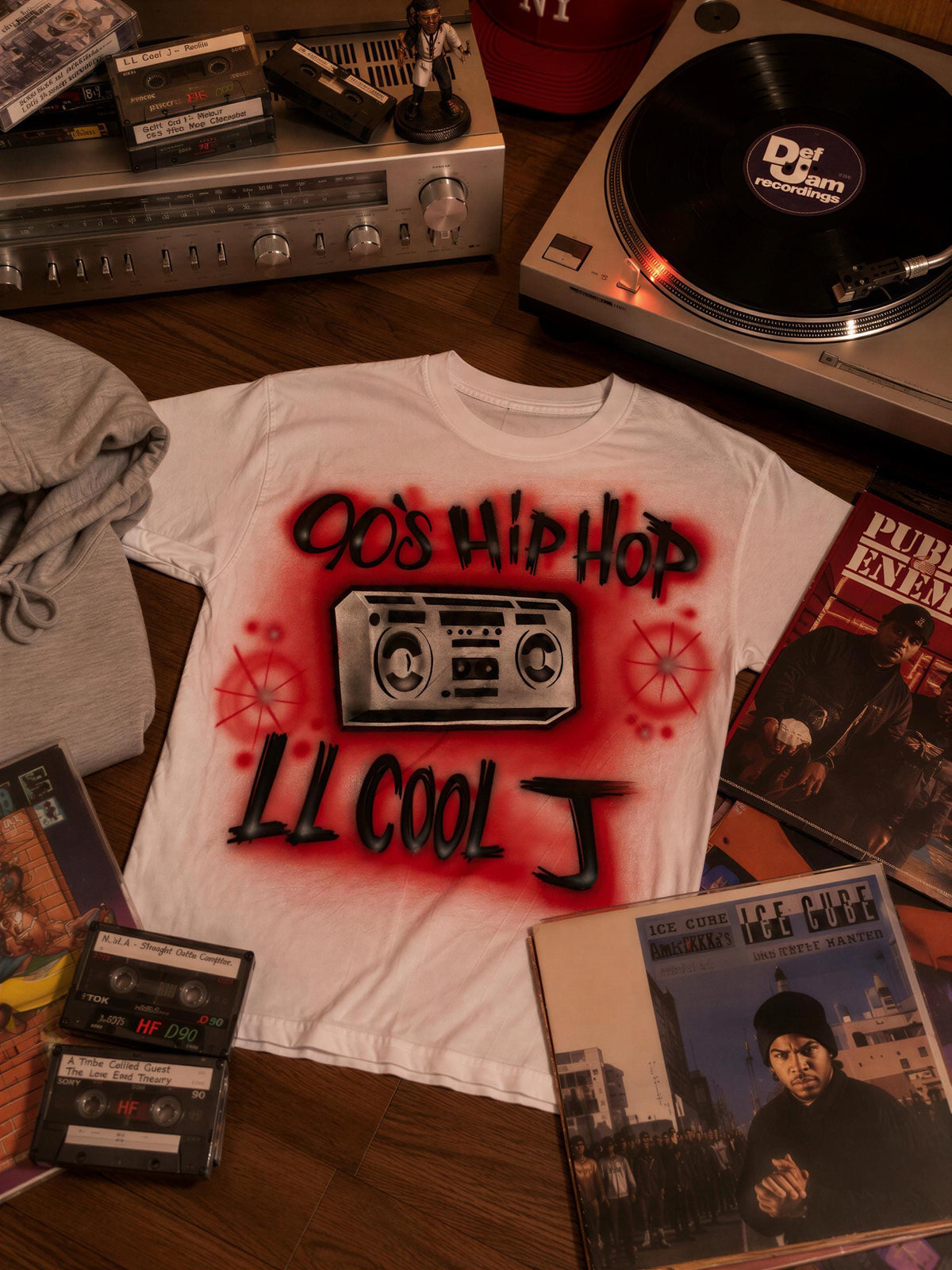 a white t-shirt with red graffiti text, surrounded by various music-related items such as cassette tapes, a turntable, and a record album.
