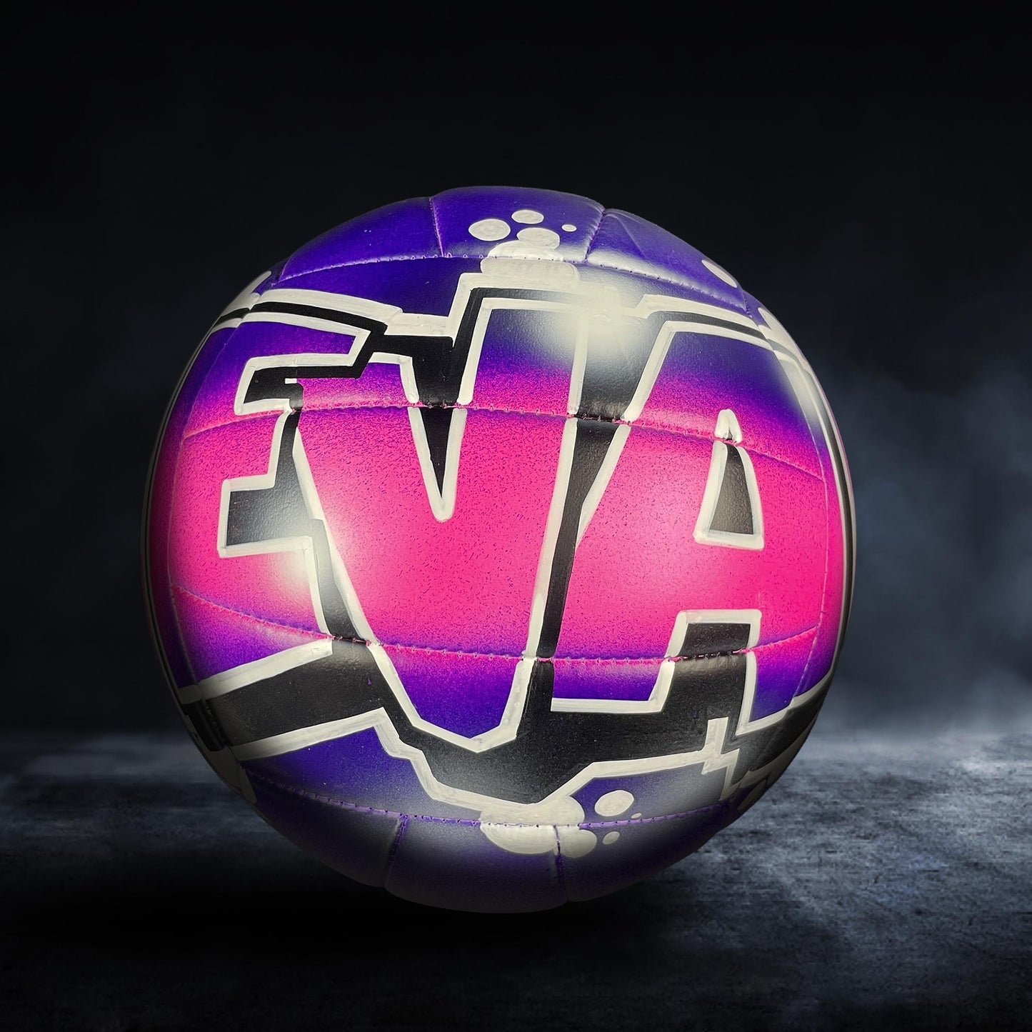 A colorful volleyball with the word "EVA" painted on it, set against a dark background.