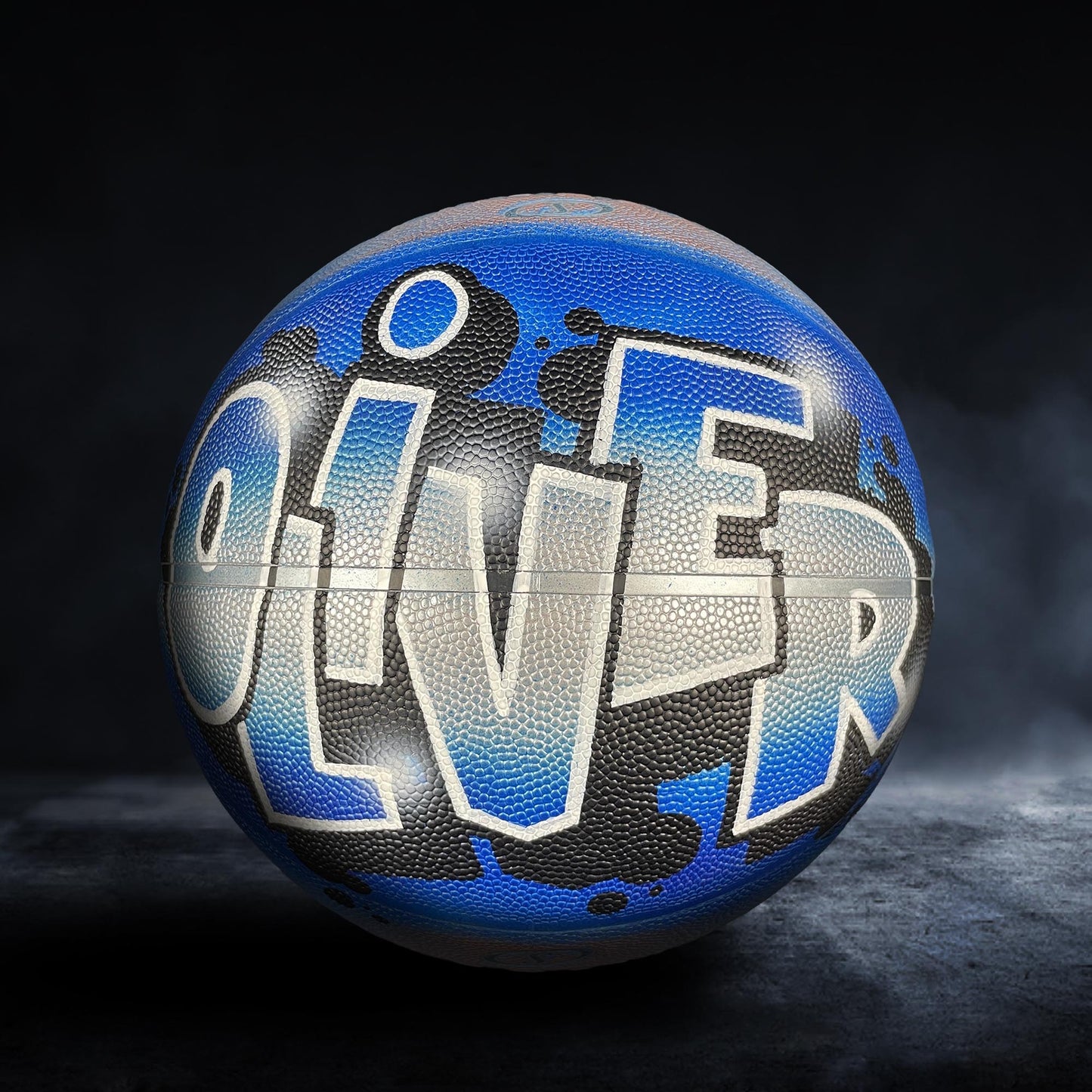 A basketball with the word "OLIVER" painted on it in blue and black colors.