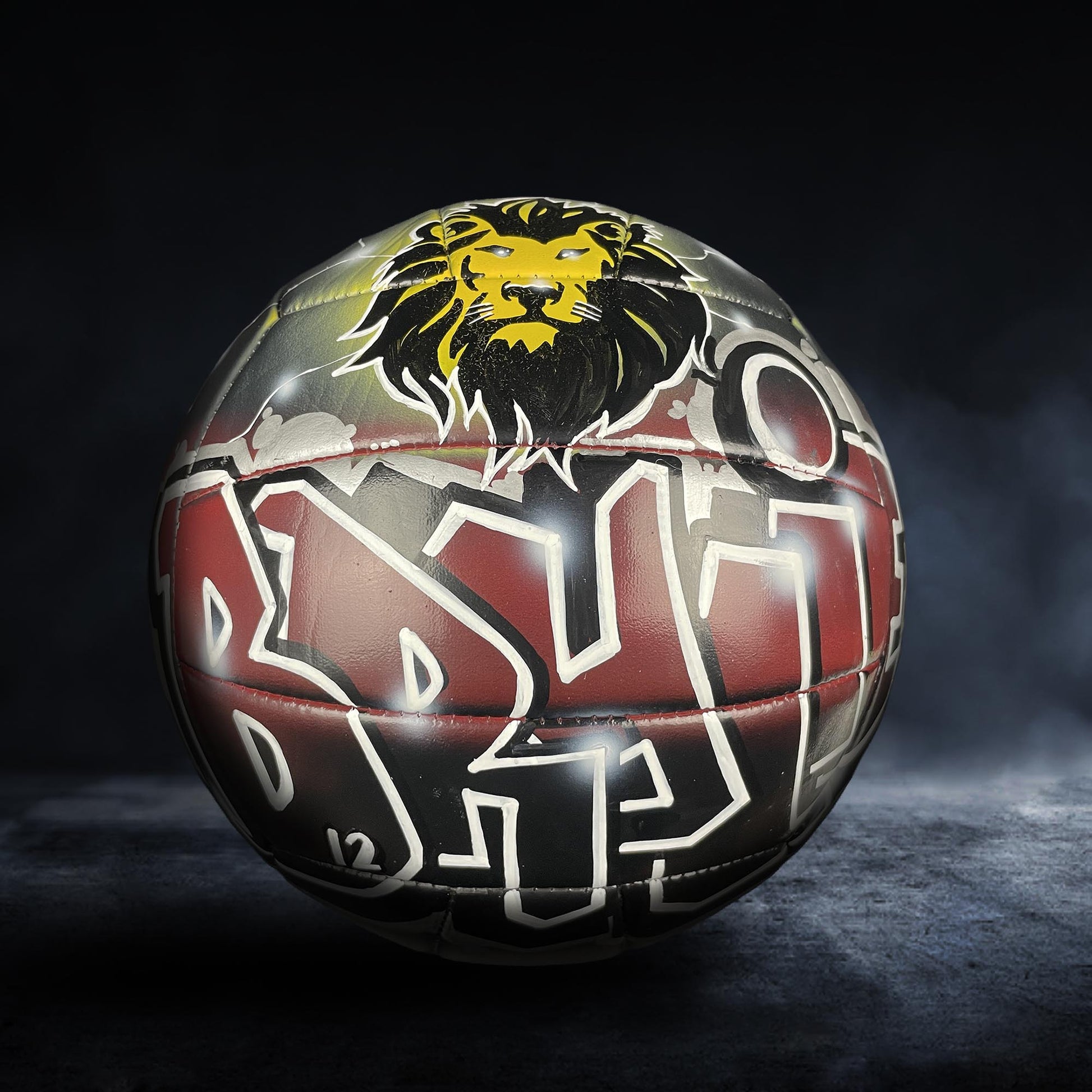 A soccer ball with a lion's head design on it, featuring a mix of red, black, and yellow colors.