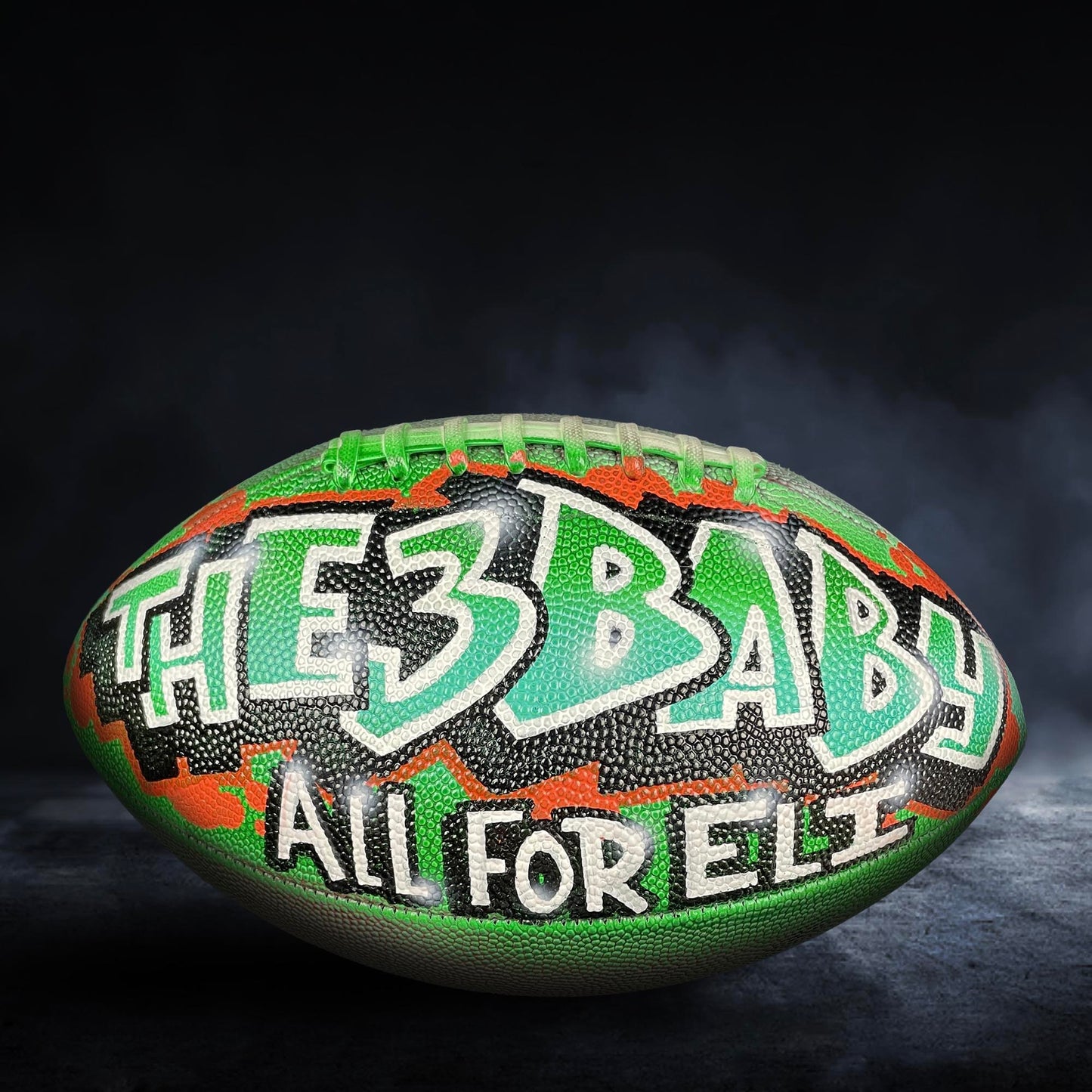 A football with the text "THE 3 BABY ALL FOR ELLE" painted on it.