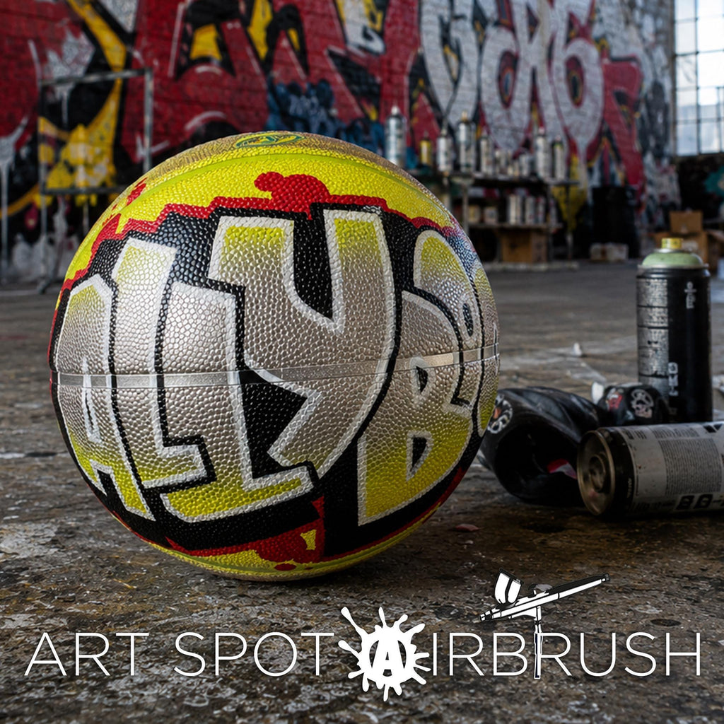 A basketball with graffiti writing on it, along with some spray paint cans and a can of spray paint, in an urban setting with graffiti on the walls in the background.
