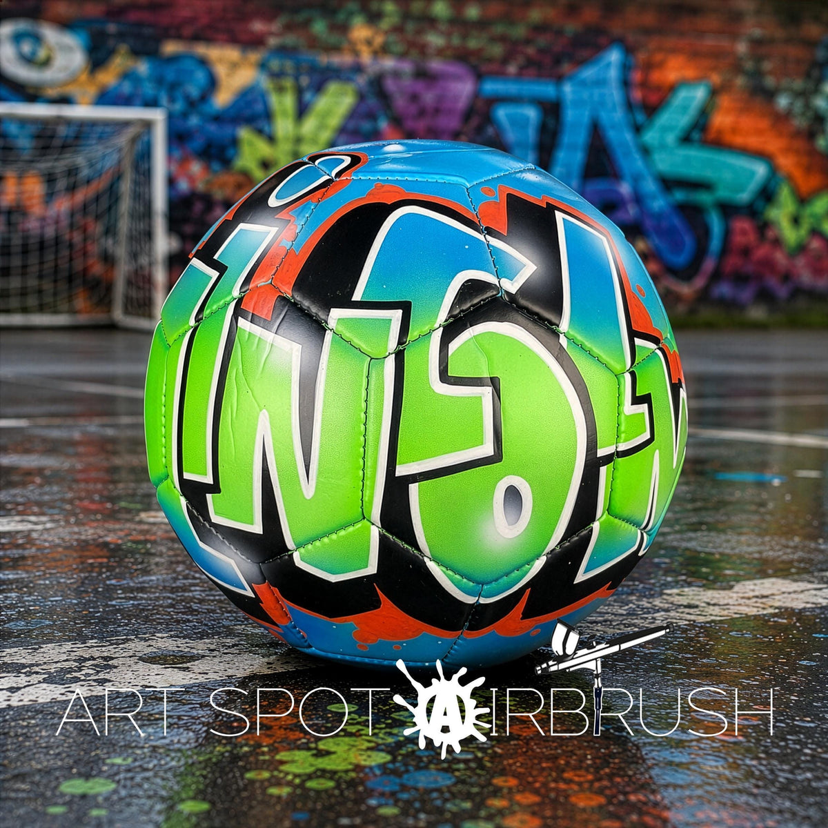 A colorful soccer ball with graffiti-style lettering is displayed on a wet surface, with a graffiti-covered wall in the background.