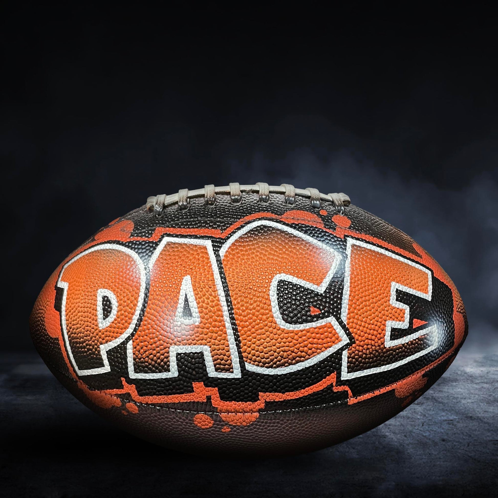 An orange and black football with the word "PACE" written on it.