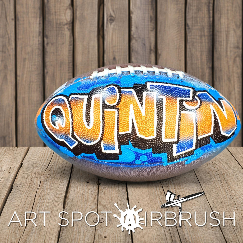 A football with the word "QUINT" painted on it, sitting on a wooden surface.