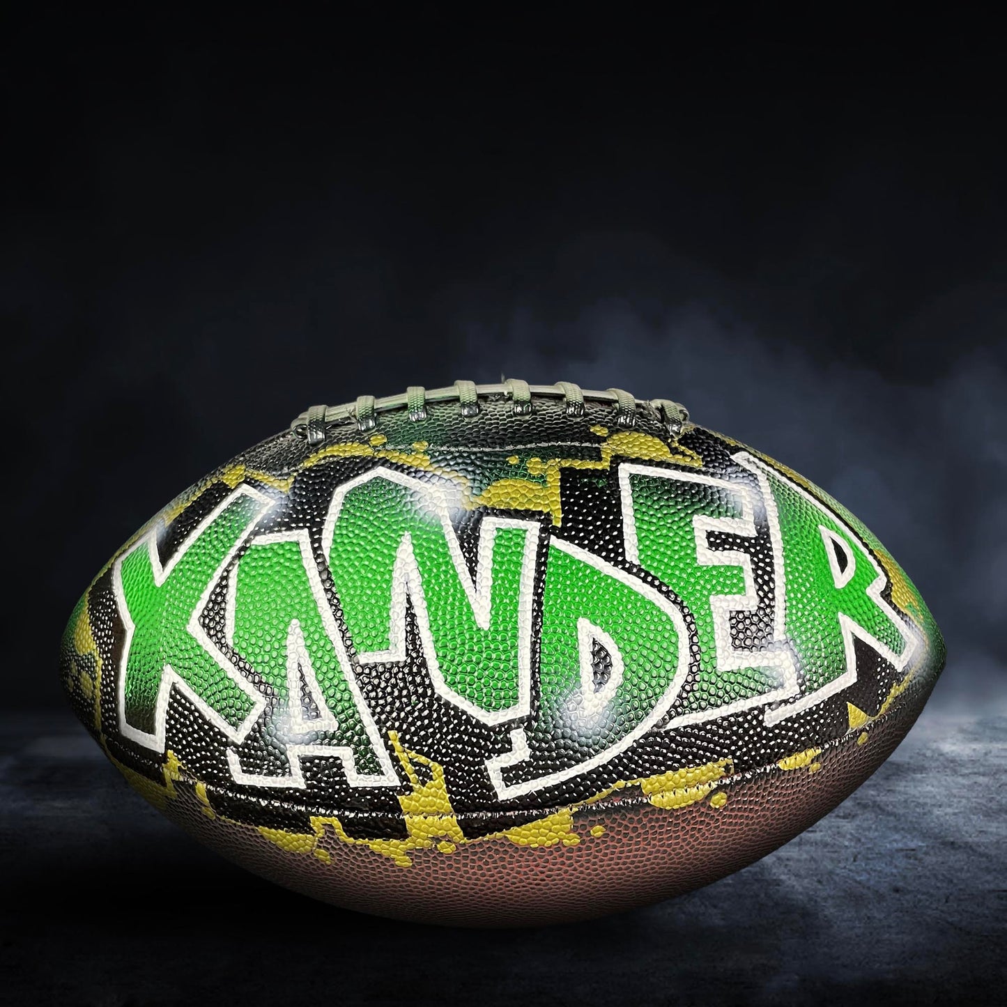 A football with the name "KANDER" painted on it in green and black colors.