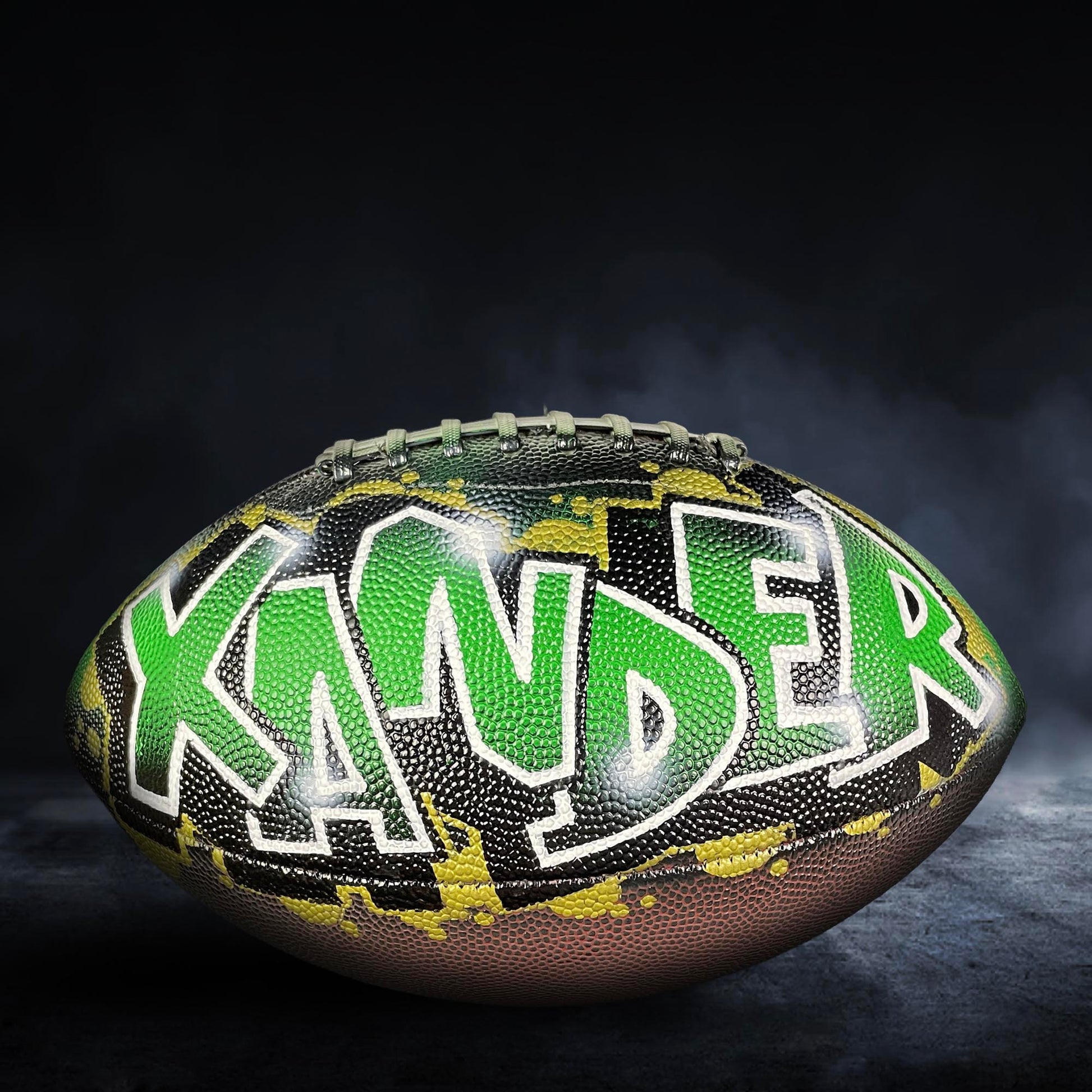 A football with the name "KANDER" painted on it in green and black colors.