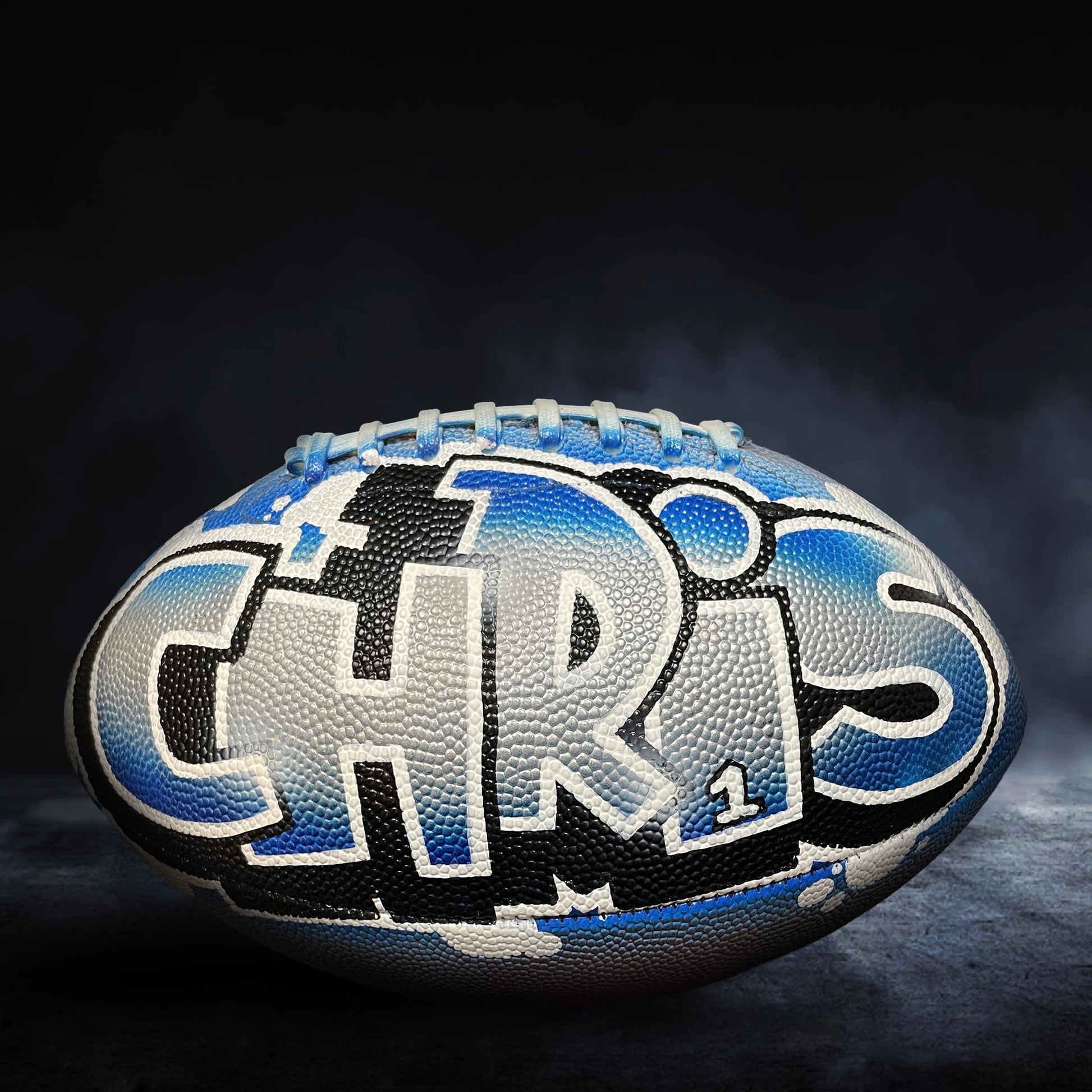 A football with the name "CHRIS" painted on it, featuring a blue and white color scheme.