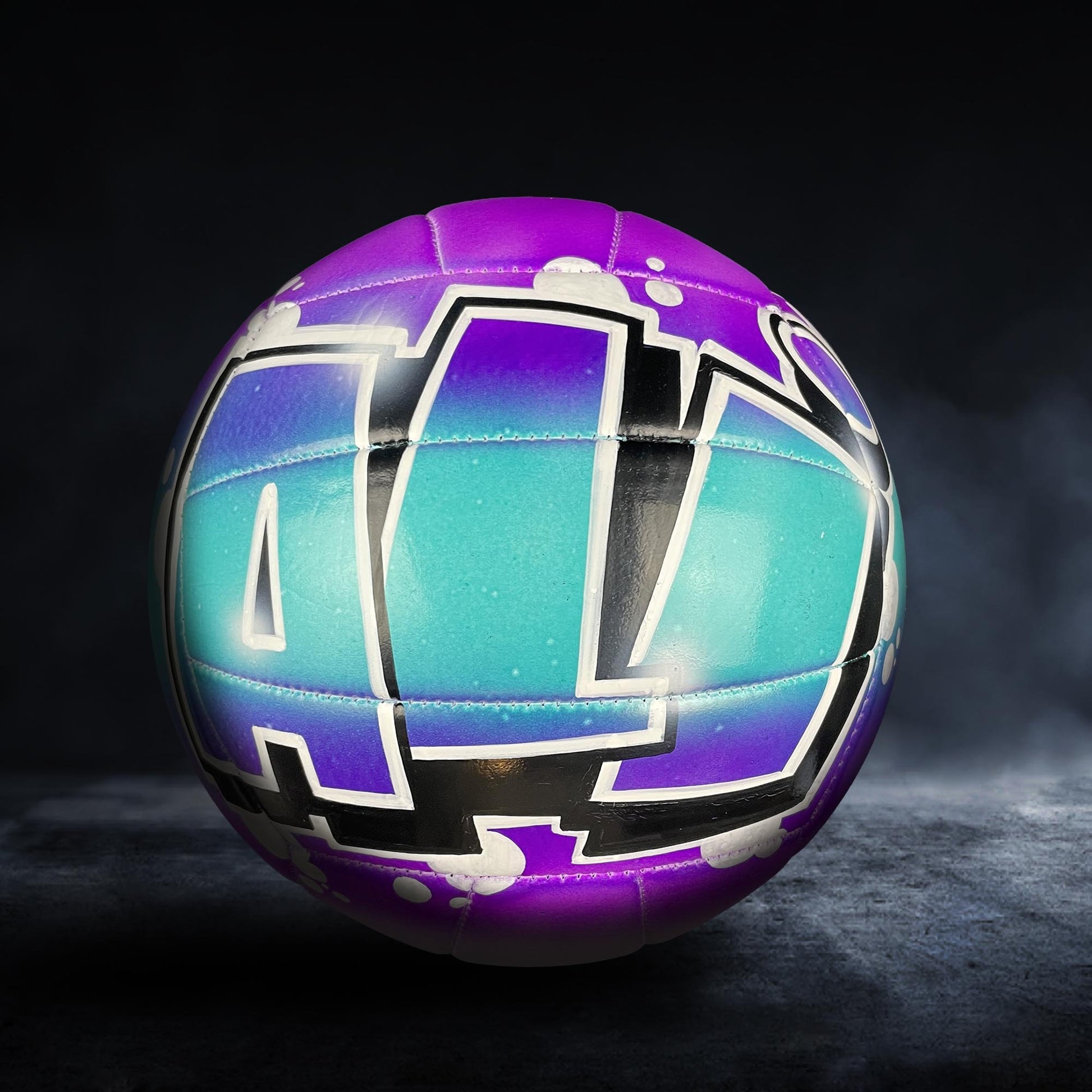A colorful volleyball with a purple and teal design, featuring the letters "AL" prominently displayed.