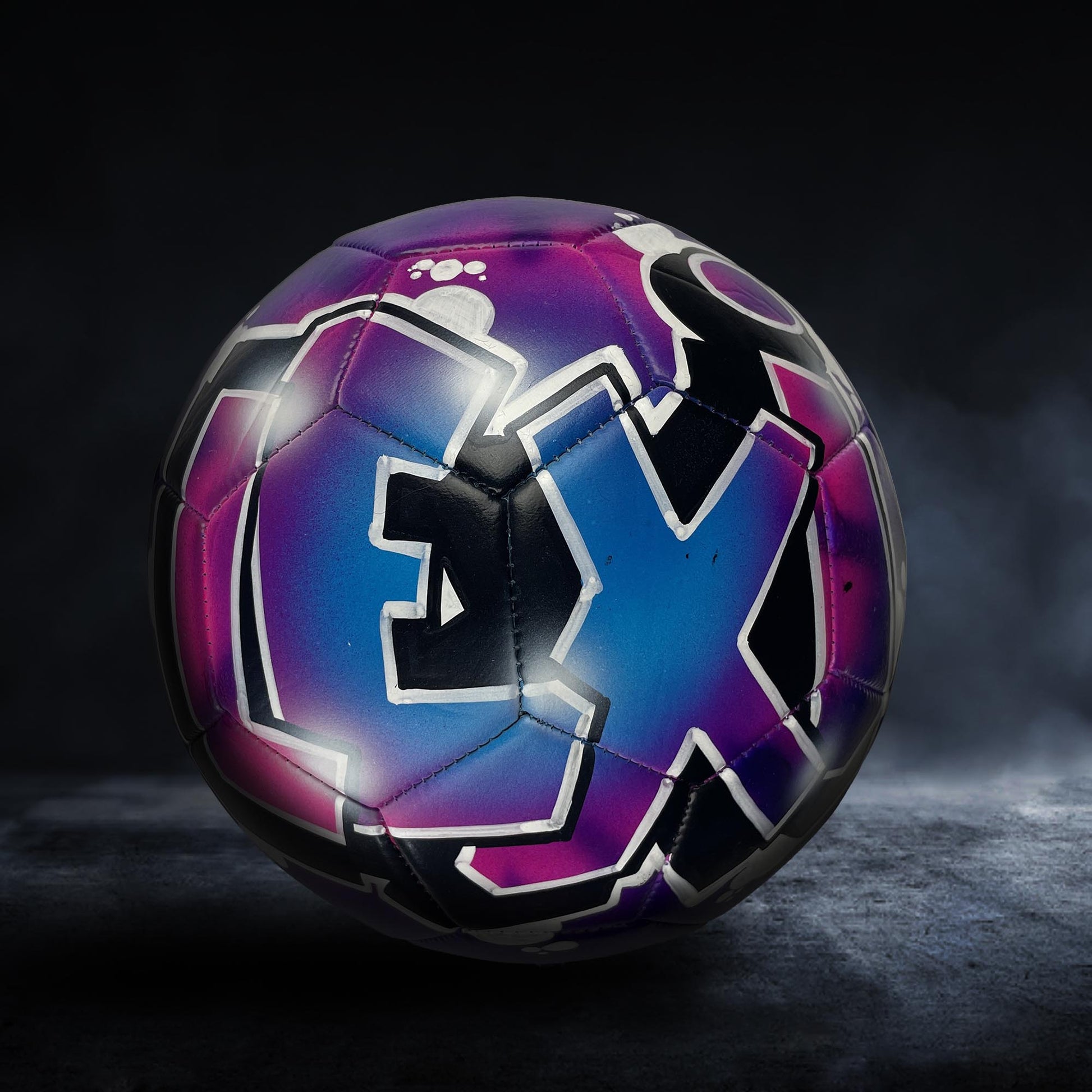 A colorful soccer ball with a graffiti-style design on it, set against a dark background.