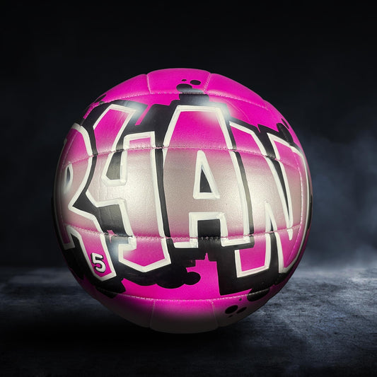 A pink and black volleyball with the name "RYAN" written on it.