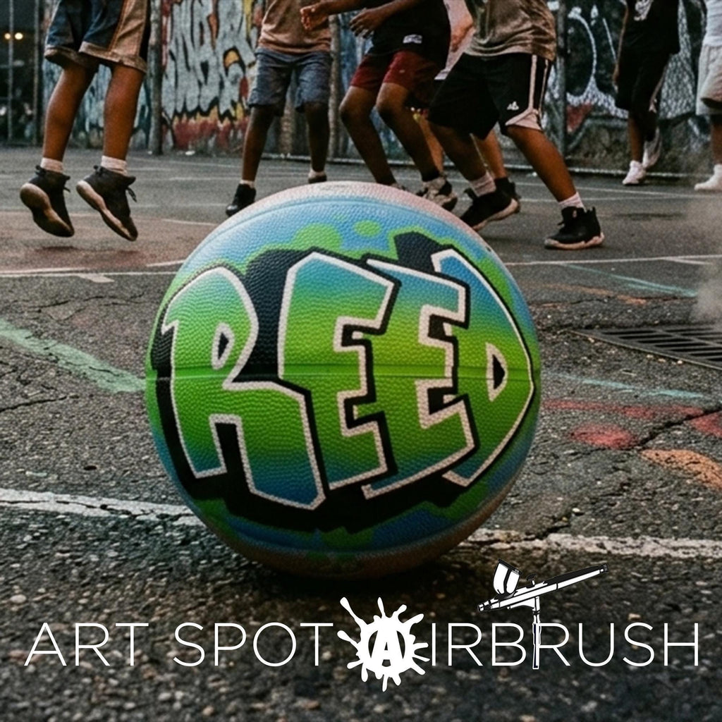 A basketball with the word "RED" painted on it, surrounded by graffiti on the ground, with people playing basketball in the background.