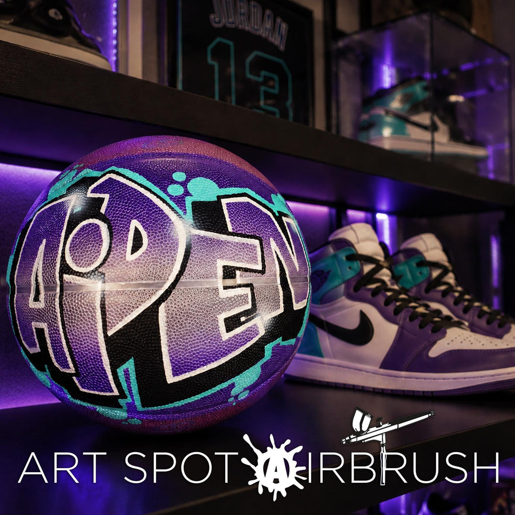 A purple basketball with the word "PEN" painted on it, along with a pair of purple and white sneakers, displayed on a shelf.