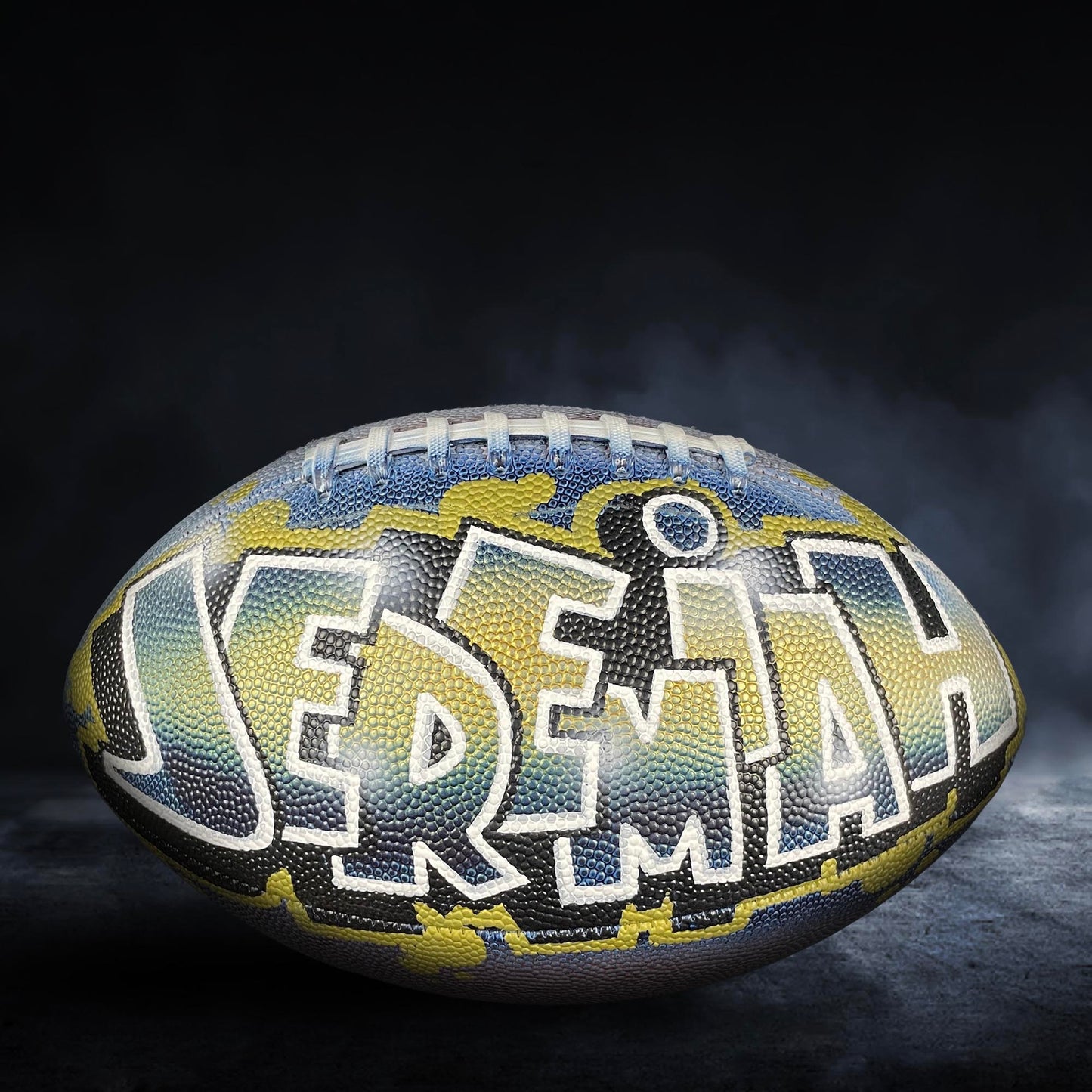 A personalized football with the name "JEREM" painted on it.