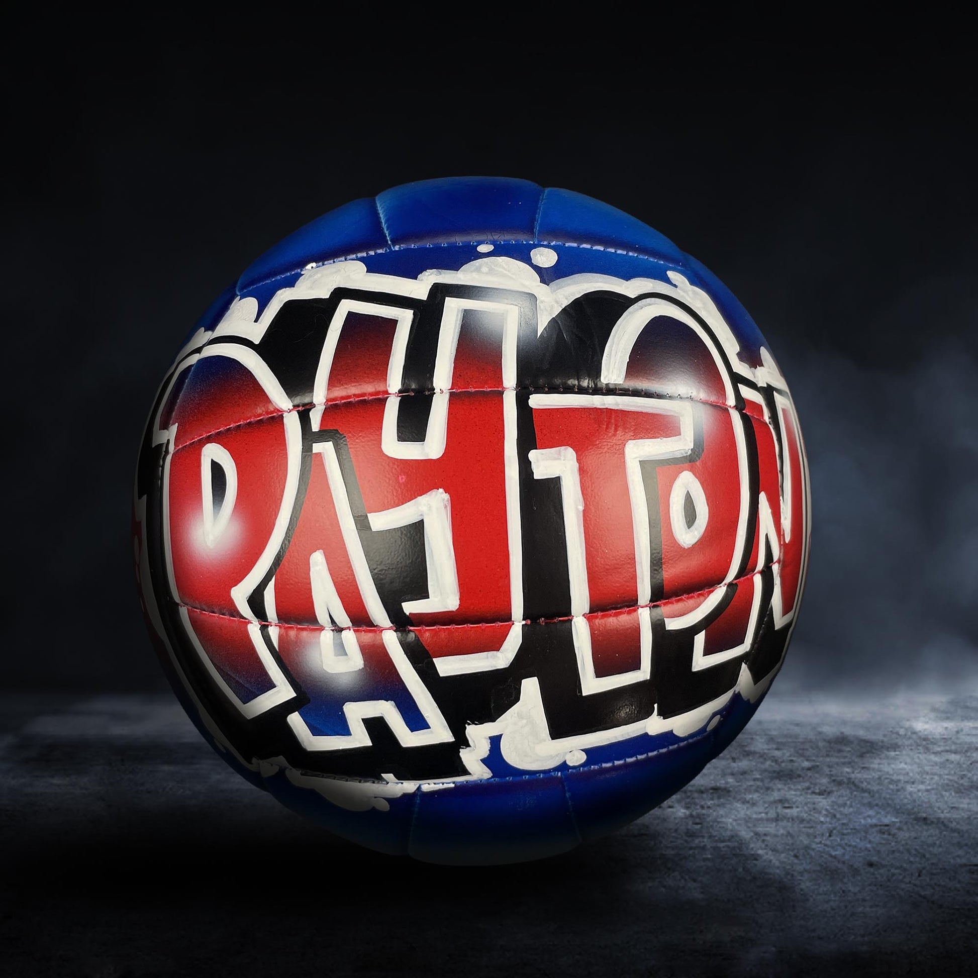 A blue and red soccer ball with the word "PATRON" written on it in graffiti-style lettering.