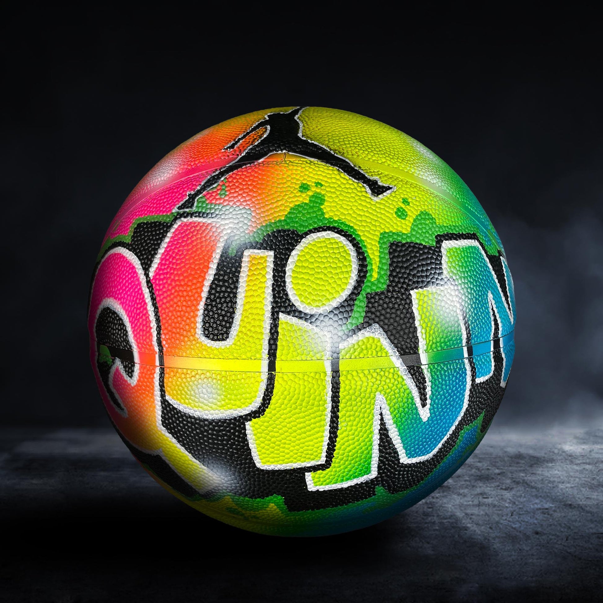 A colorful basketball with graffiti-style lettering on it, set against a dark background.