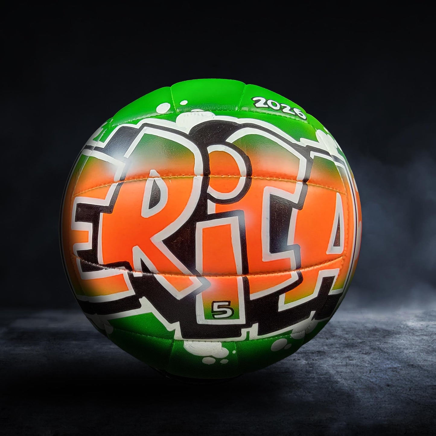 A green and orange sports ball with the text "ERICA" printed on it, against a dark background.
