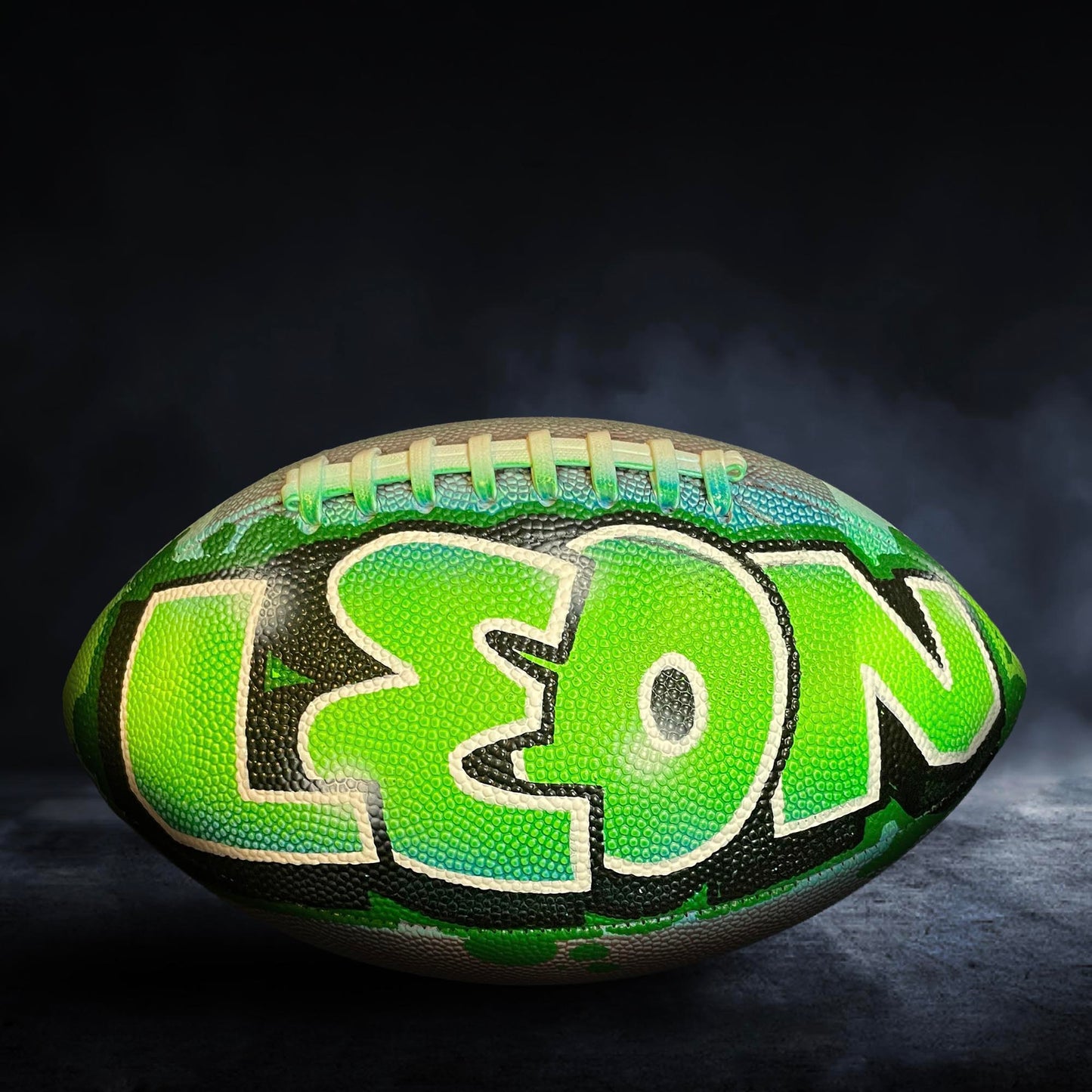 A green and black football with the name "LEON" painted on it.