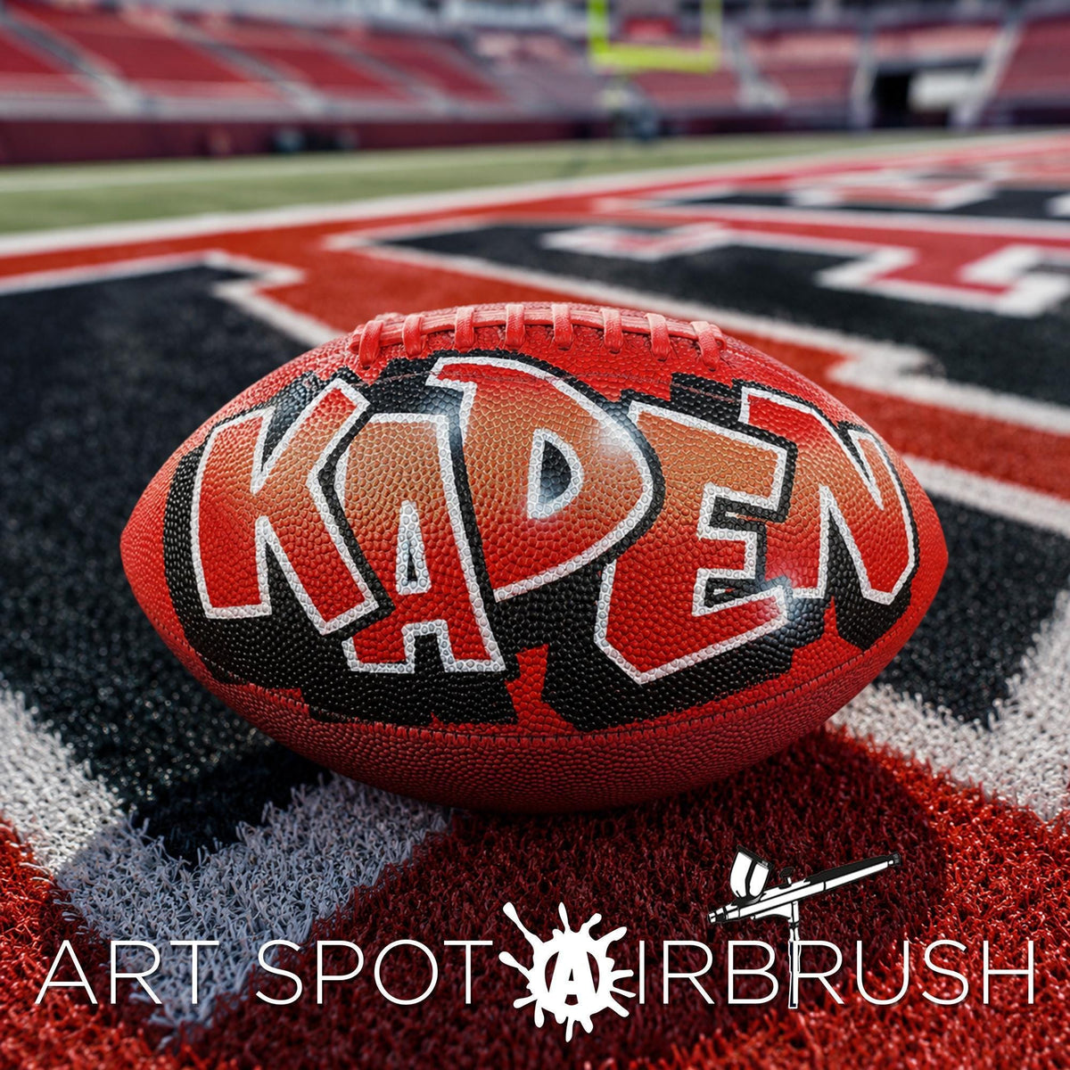 A red and black custom football personalized with the word "KADEN" written on it, placed on a red and black patterned surface.