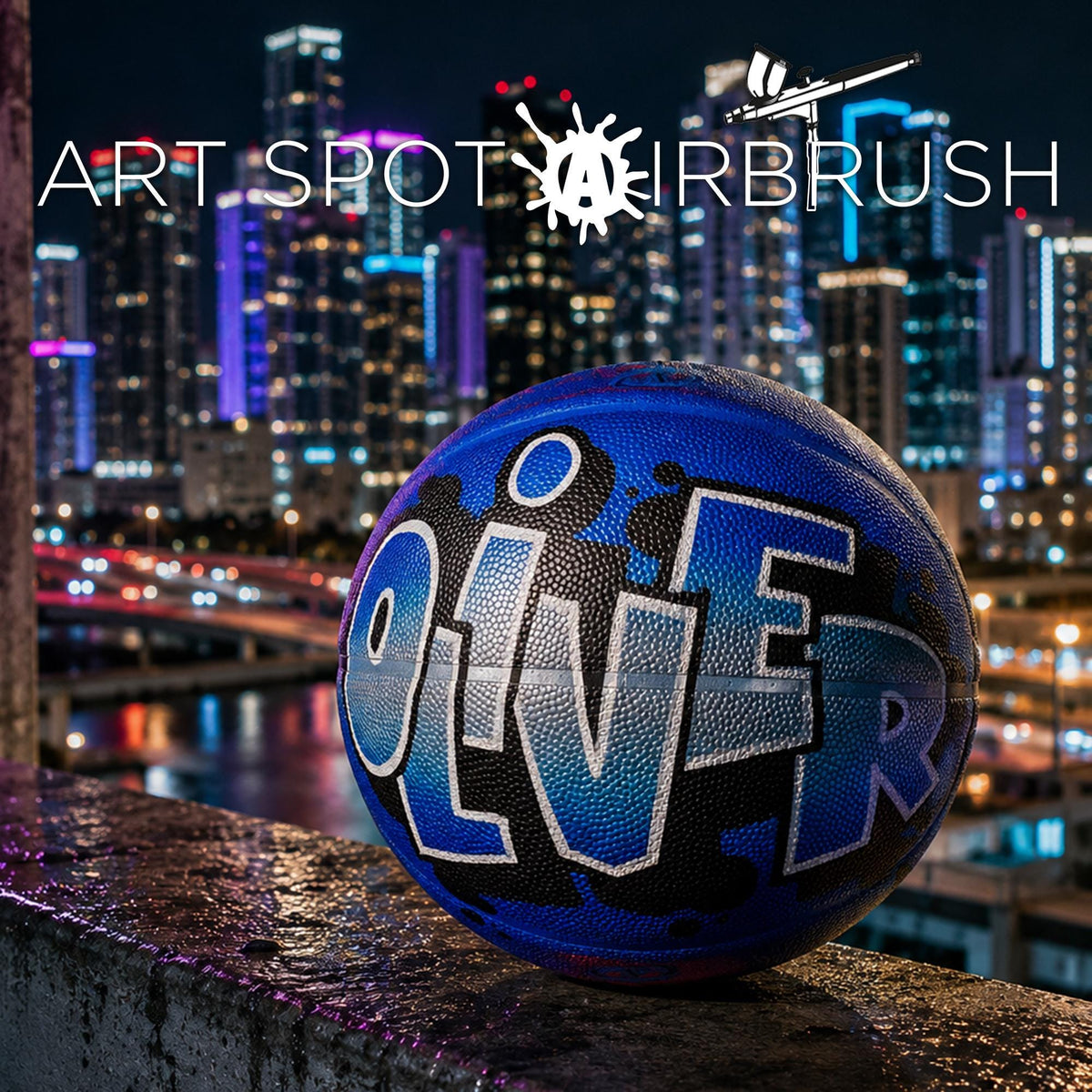 A basketball with the name "OLIVER" painted on it, sitting on a ledge against a backdrop of a city skyline at night.