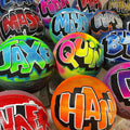 A collection of colorful basketballs with various graffiti-style names and designs painted on them.