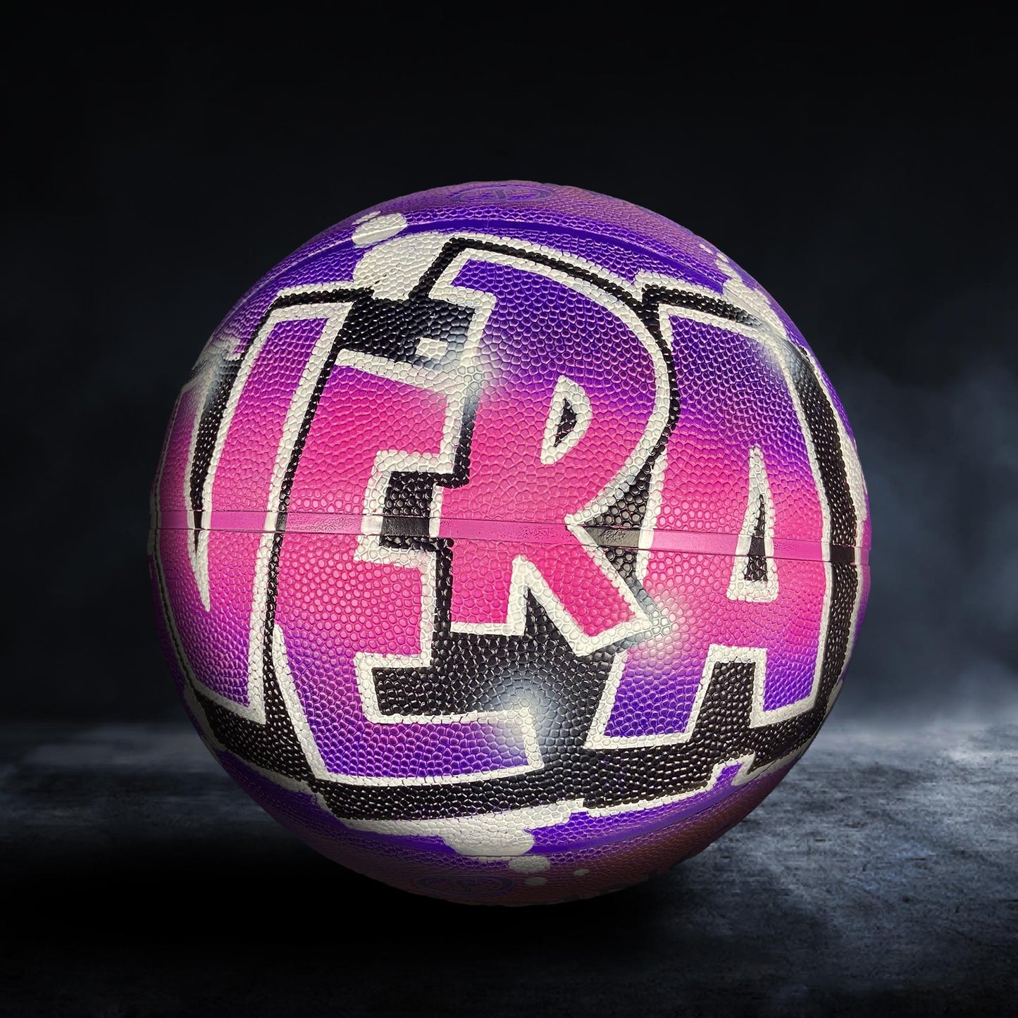A colorful basketball with the word "VERA" painted on it, set against a dark background.
