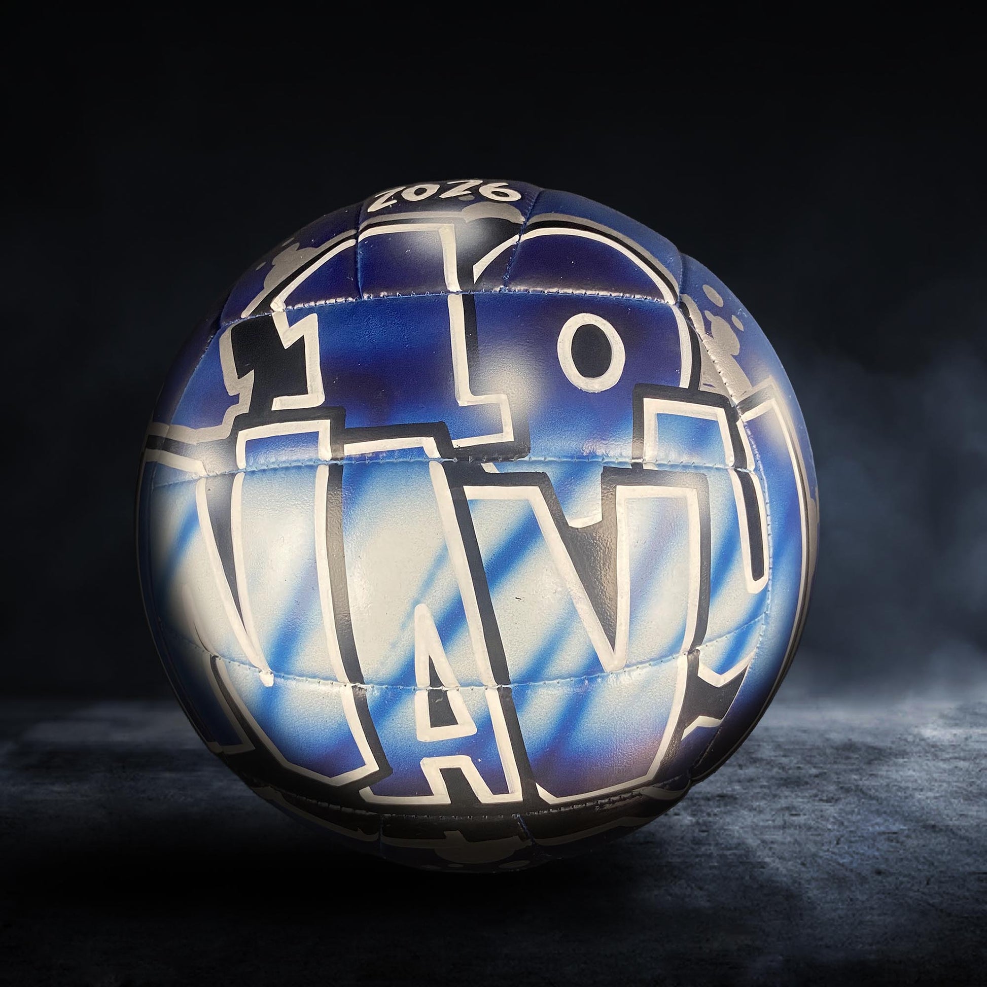 A blue and white sports ball with the text "N" prominently displayed on it, set against a dark background with a misty effect.