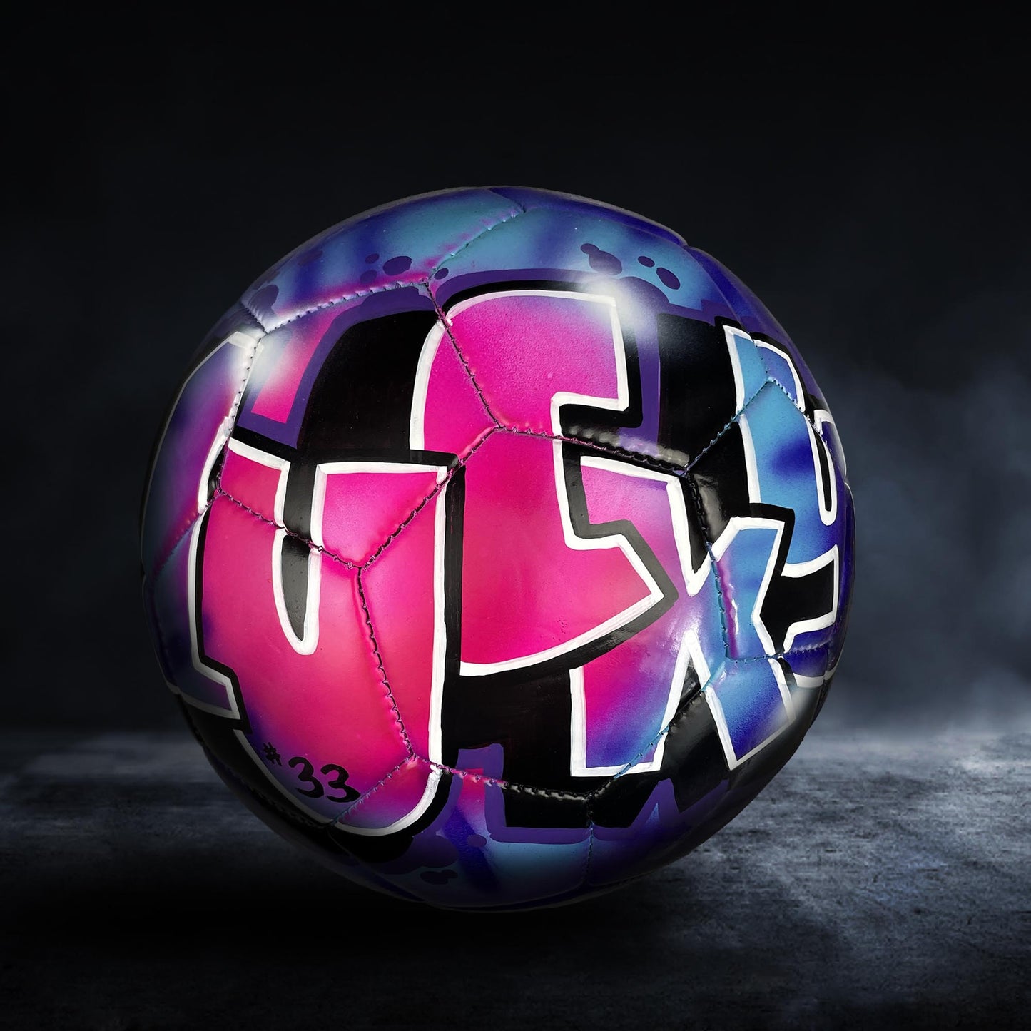 A colorful soccer ball with graffiti-style lettering on it, set against a dark background.