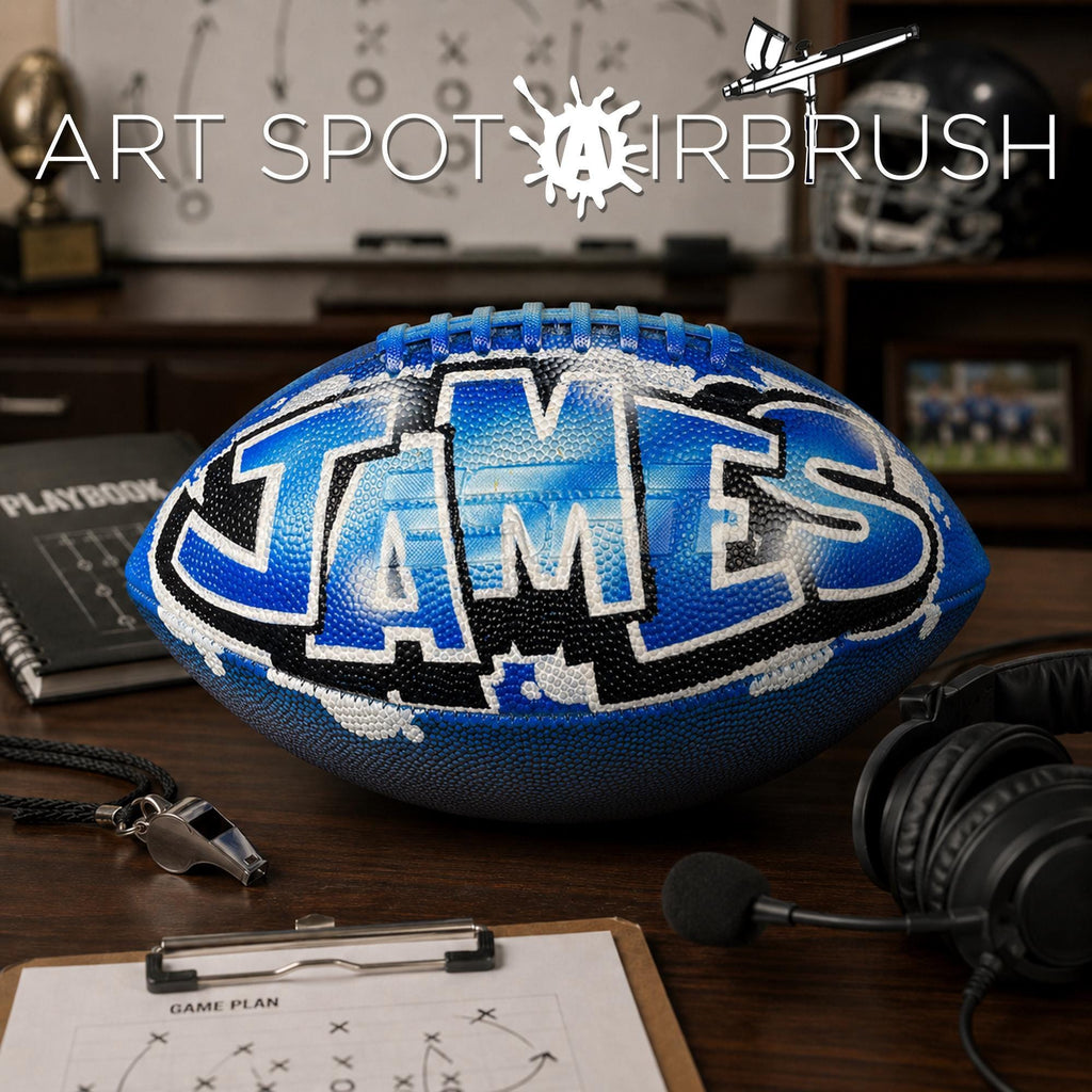 a personalized football with the name "JAMES" painted on it, sitting on a desk surrounded by various sports equipment and a clipboard with a game plan.