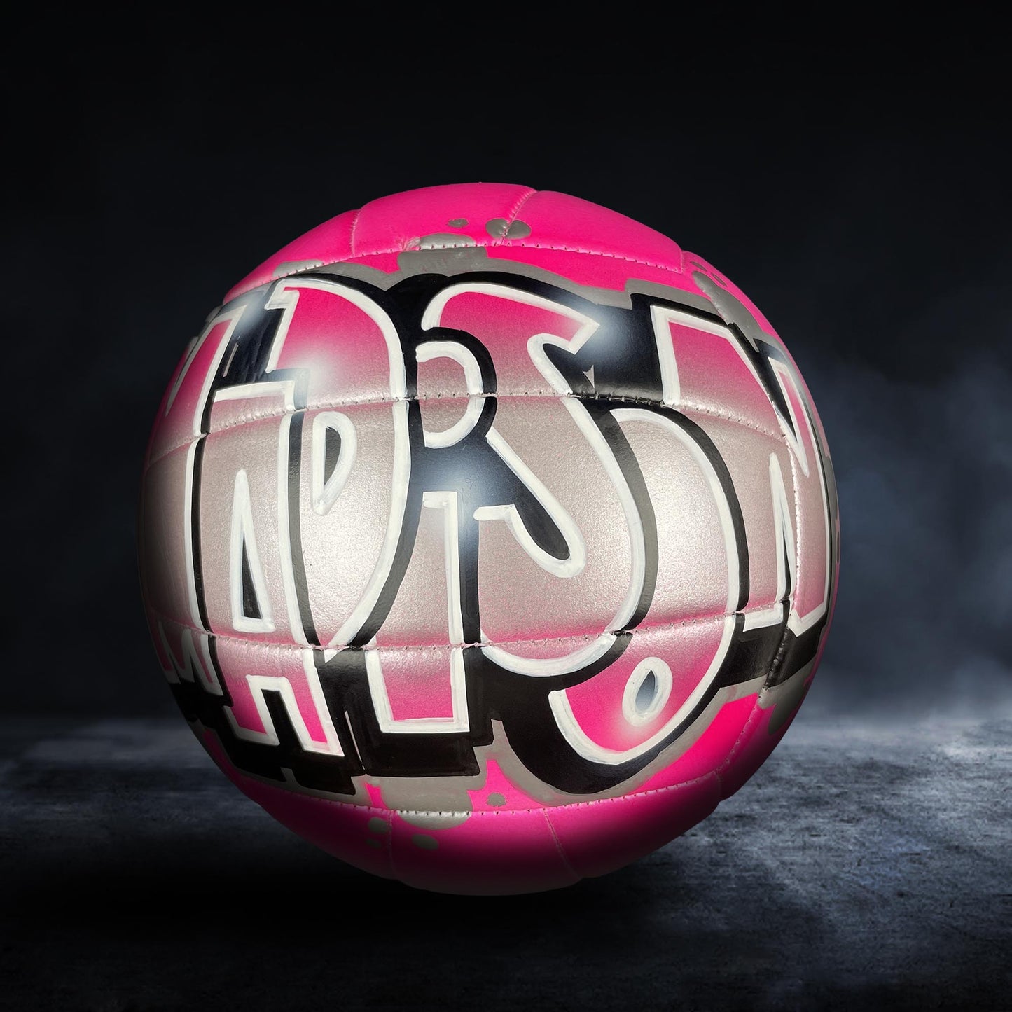 A pink and black soccer ball with the word "LARSON" painted on it.