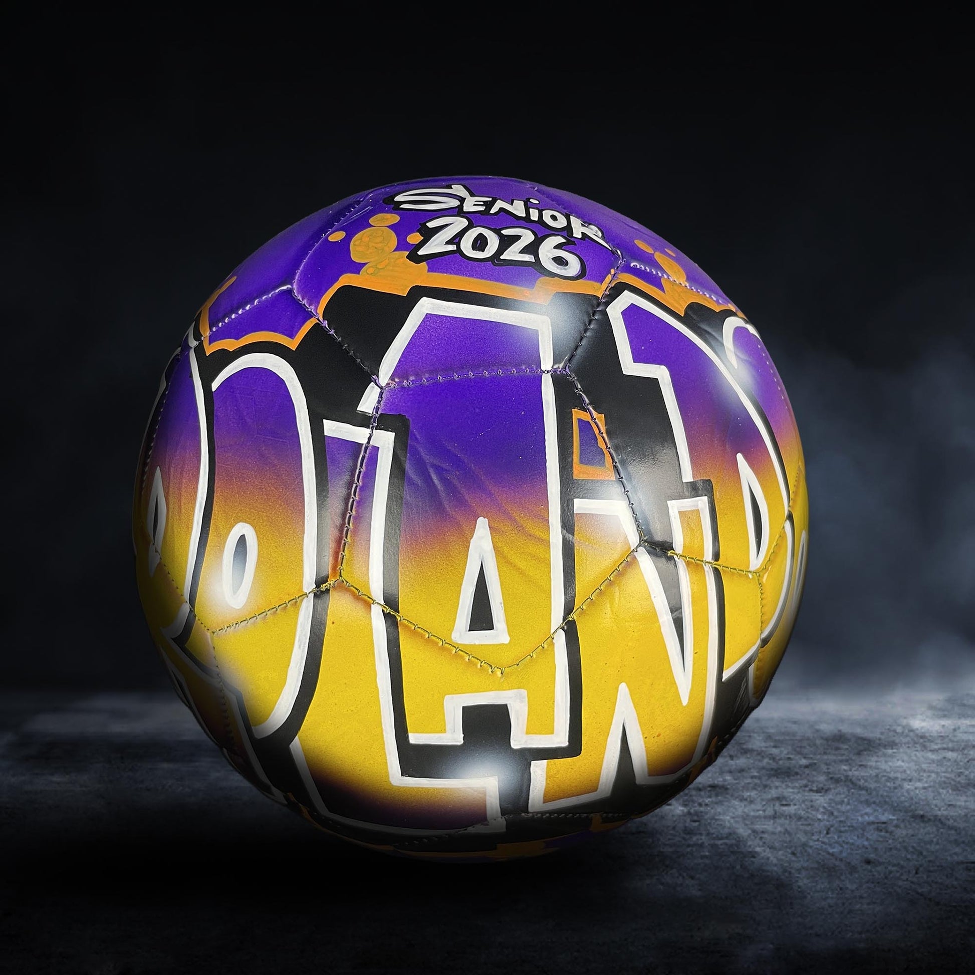 A colorful soccer ball with the text "SENIOR 2026" printed on it, set against a dark background.