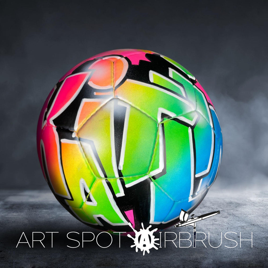 A colorful, graffiti-style soccer ball with a vibrant, abstract design on it, set against a dark background with smoke or fog.