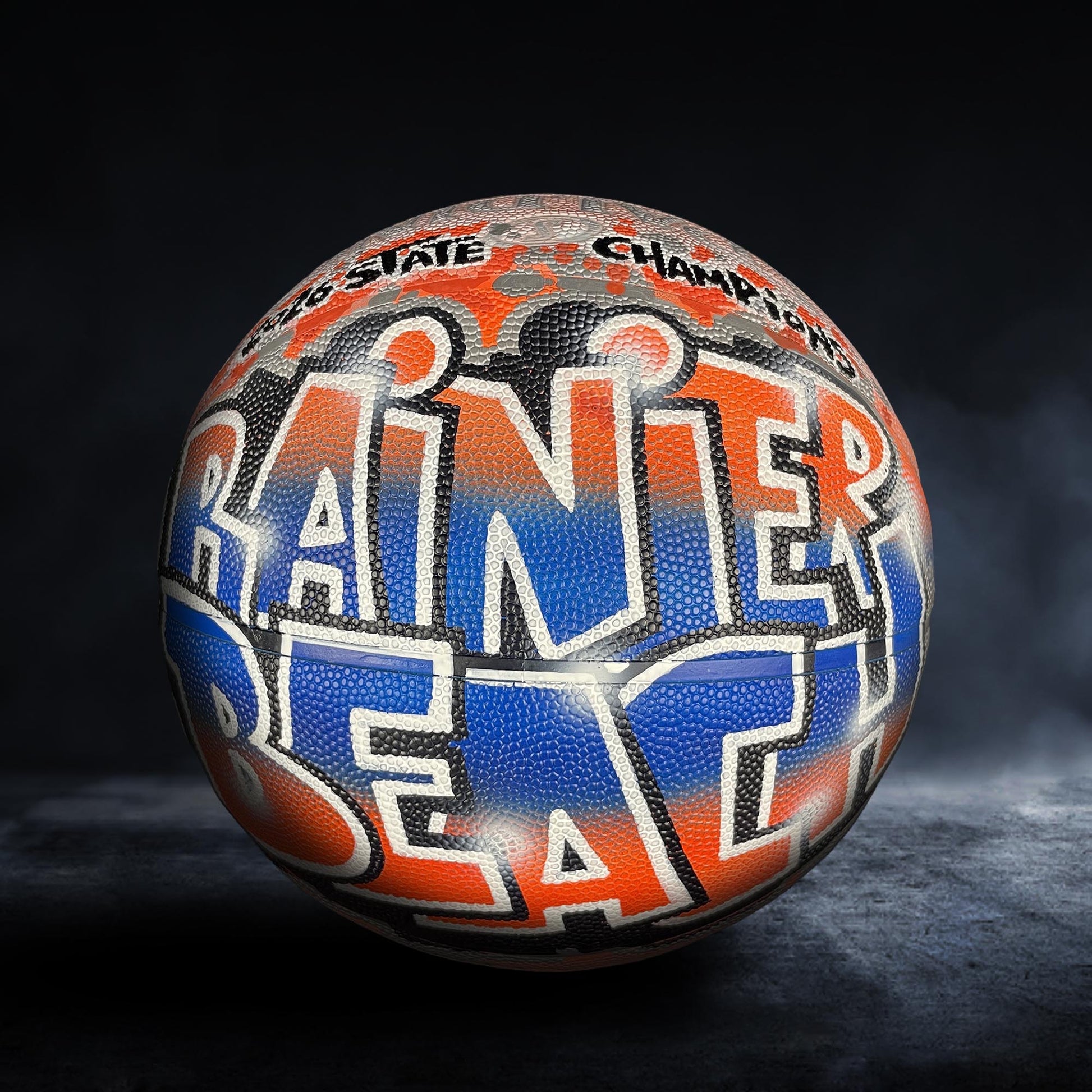 A basketball with the word "RAINER" written on it in a stylized font.