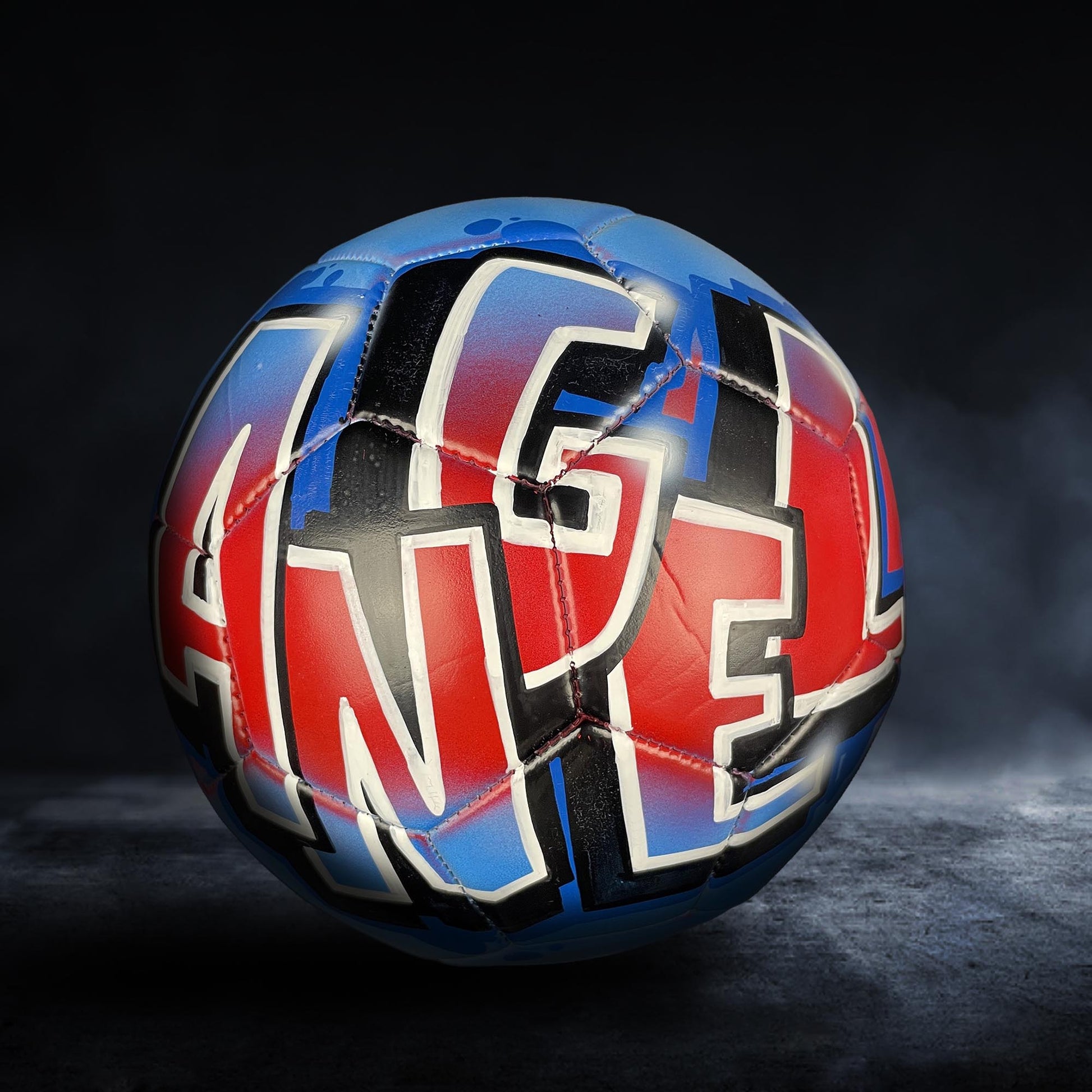 A soccer ball with the word "ANGEL" painted on it in a stylized, colorful design.