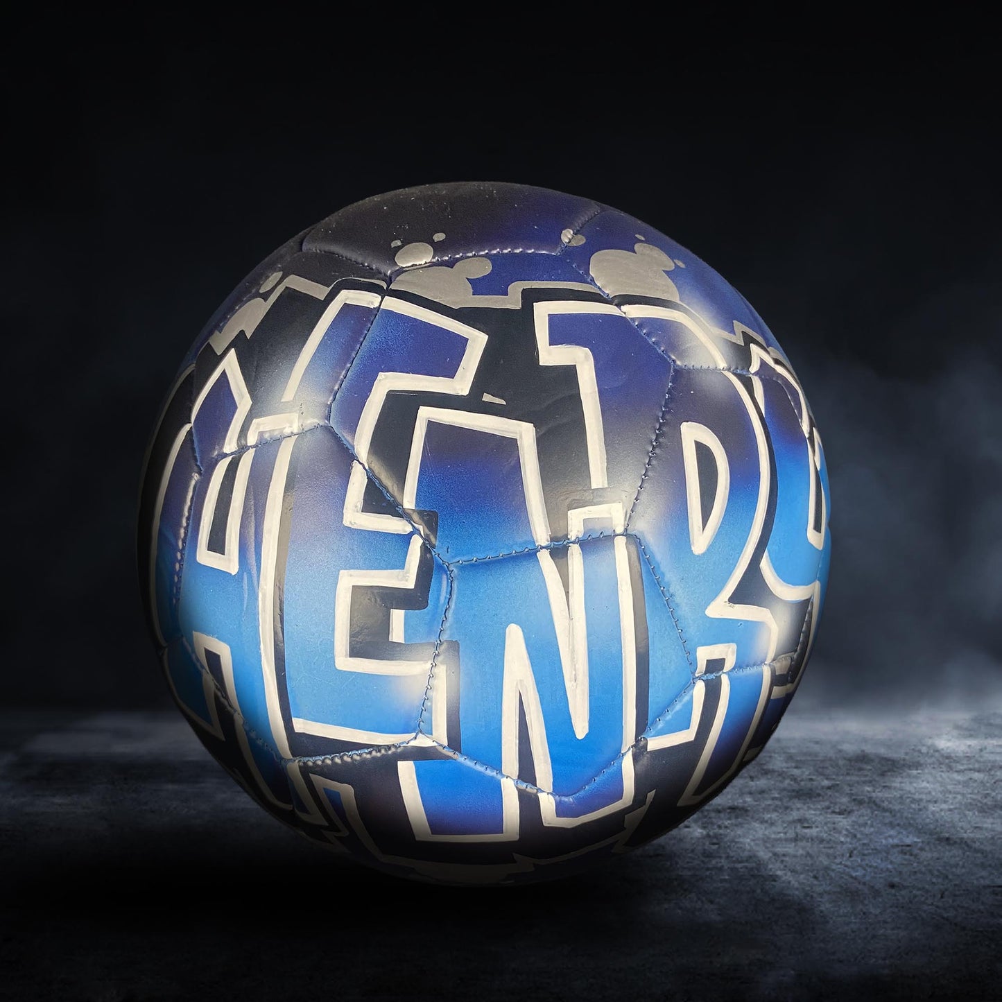 A soccer ball with the name "HENRY" painted on it in blue and white colors.