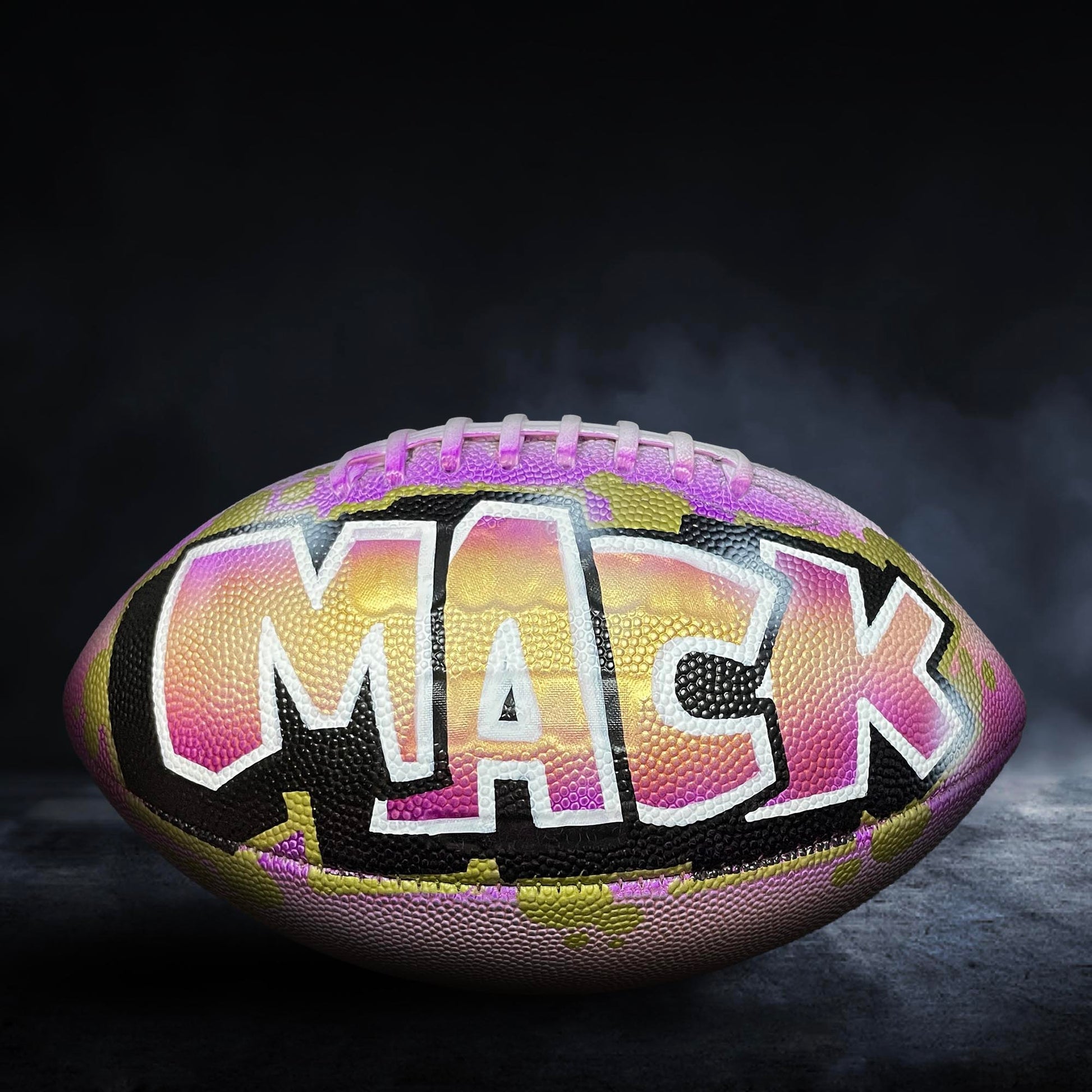 A football with the name "MACK" painted on it, featuring a colorful and vibrant design.