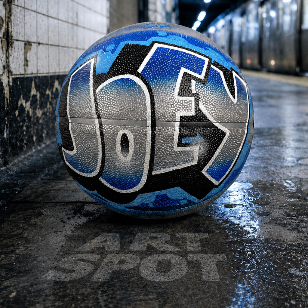 A basketball with the word "JOEY" painted on it, sitting on a wet surface.