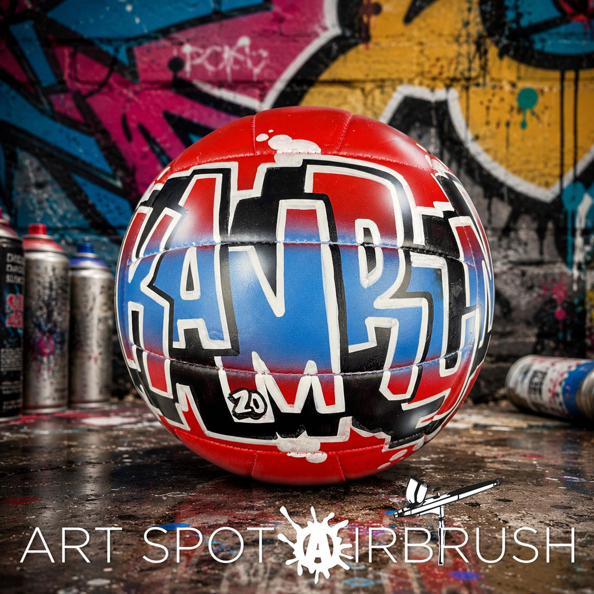 A red and blue custom volleyball personalized with graffiti text on it, placed on a surface with graffiti art in the background.