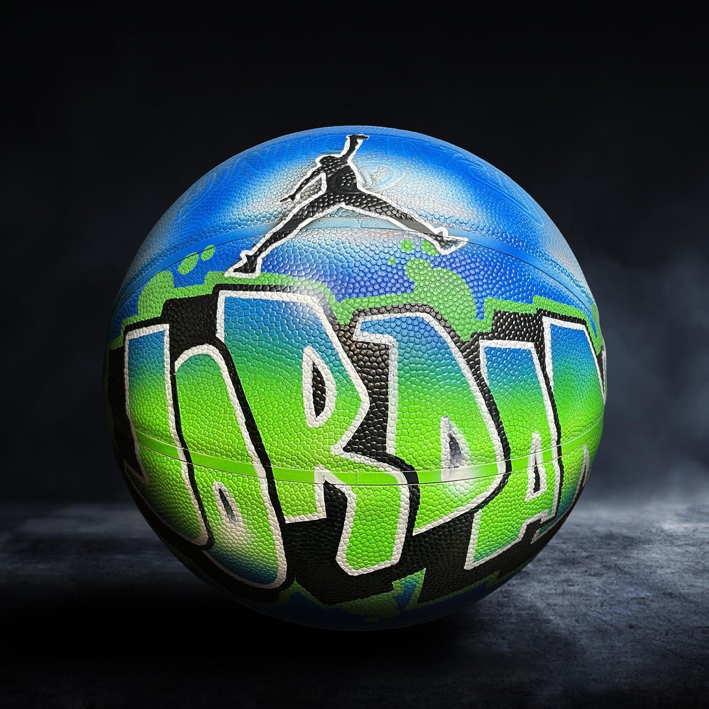 A basketball with the word "JORDAN" painted on it in graffiti-style lettering.