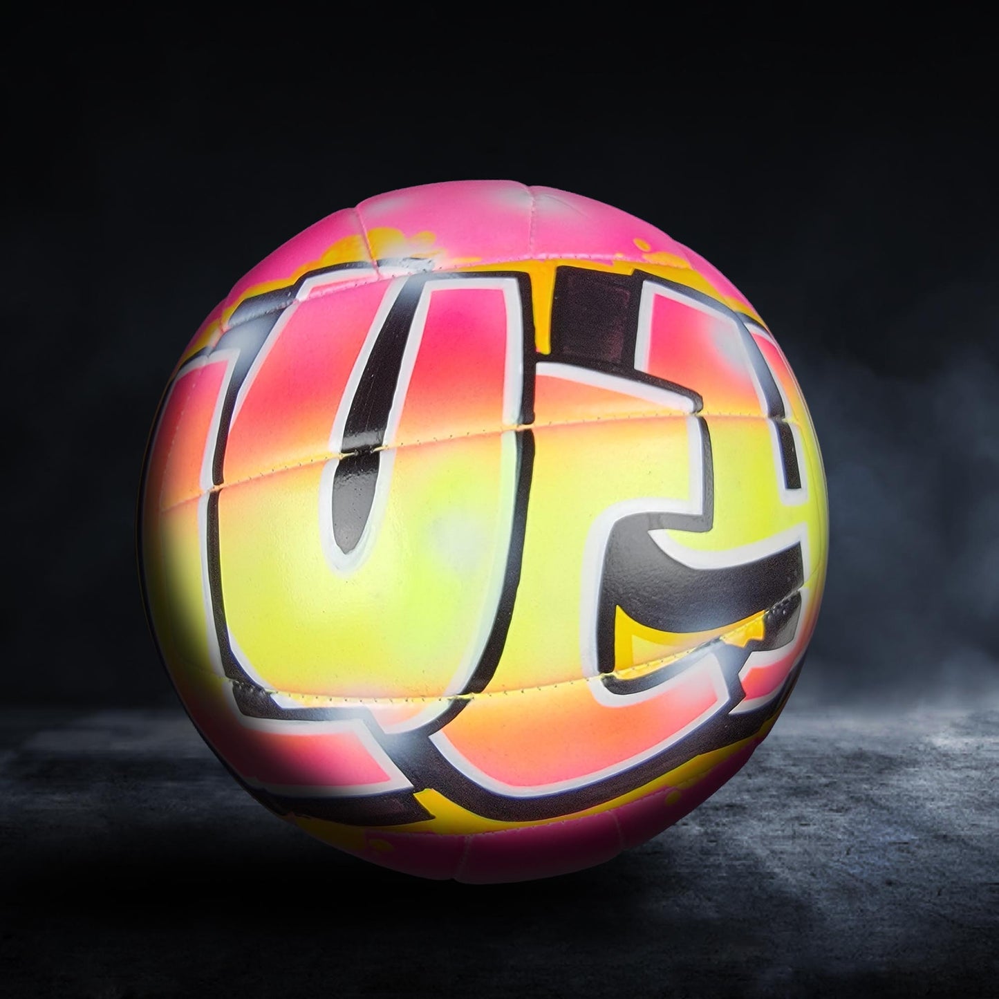 A colorful, graffiti-style volleyball with a vibrant pink and yellow design.