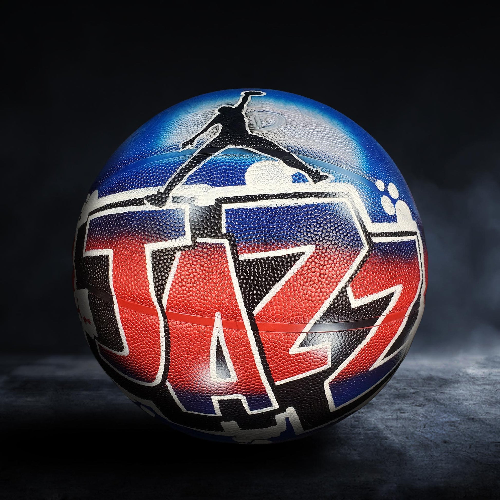 A basketball with the word "Jazz" painted on it, featuring a stylized graphic of a basketball player in mid-jump.
