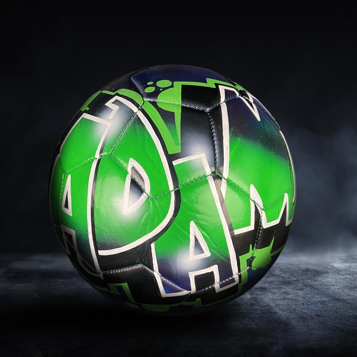 A soccer ball with a colorful, graffiti-style design on it, featuring a mix of green, blue, and black colors.
