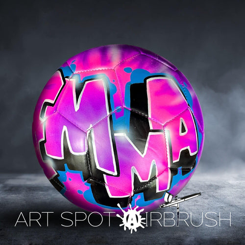 A colorful soccer ball with the word "MMA" painted on it, against a dark background.