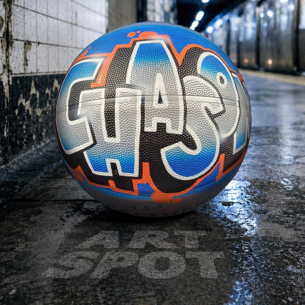 A basketball with graffiti text on it, resting on a wet surface.
